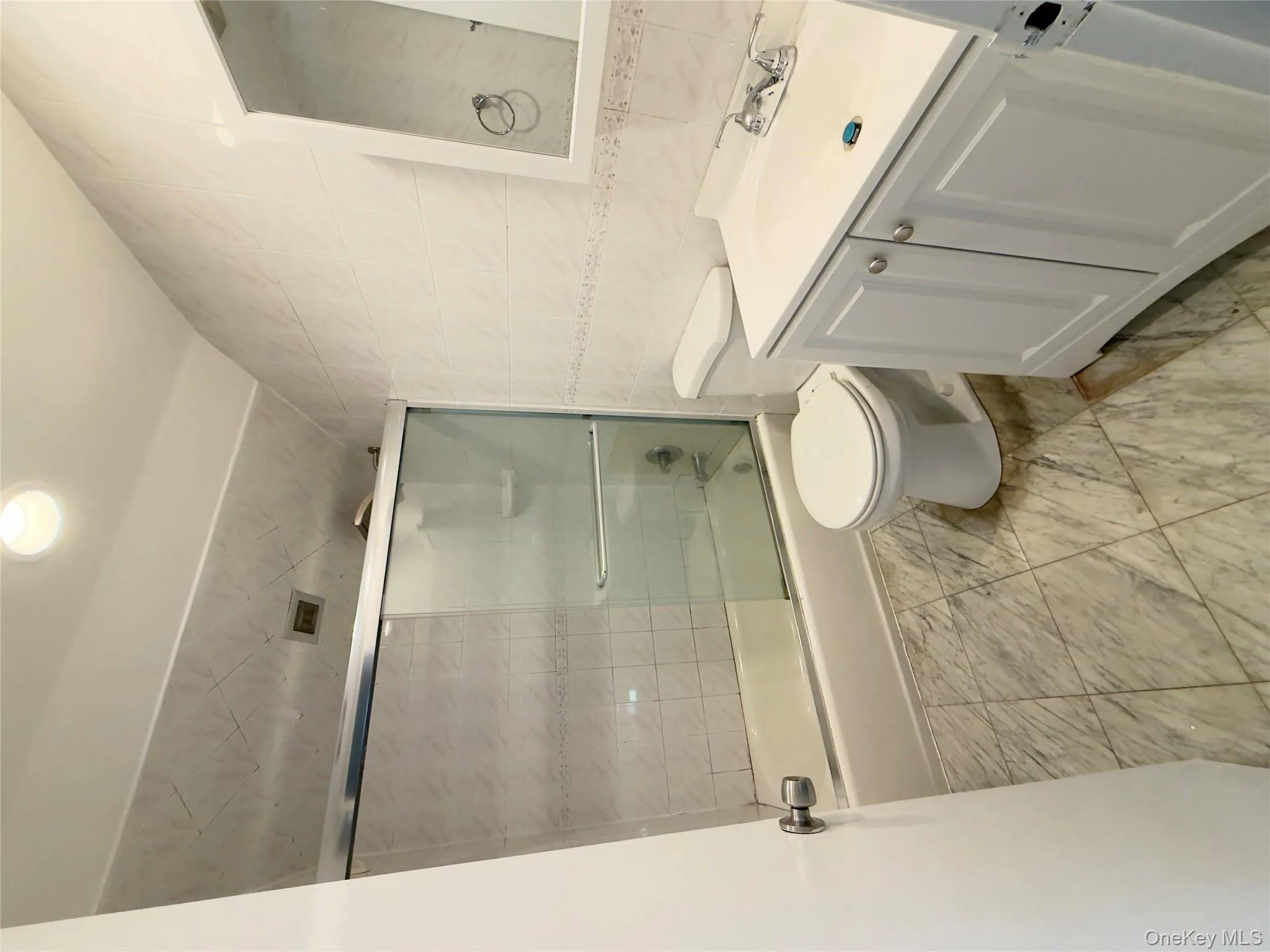 Bathroom featuring tile walls, vanity, bath / shower combo with glass door, vaulted ceiling, and recessed lighting Bathroom featuring tile walls, vanity, bath / shower combo with glass door, vaulted ceiling, and recessed lighting