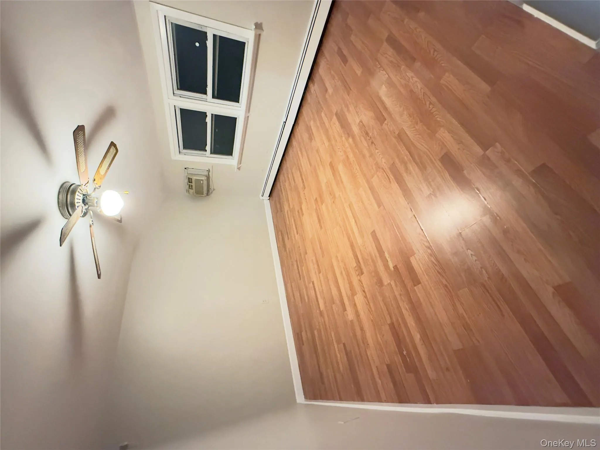 Spare room featuring a baseboard heating unit, light wood-style floors, ceiling fan, and an AC wall unit Spare room featuring a baseboard heating unit, light wood-style floors, ceiling fan, and an AC wall unit
