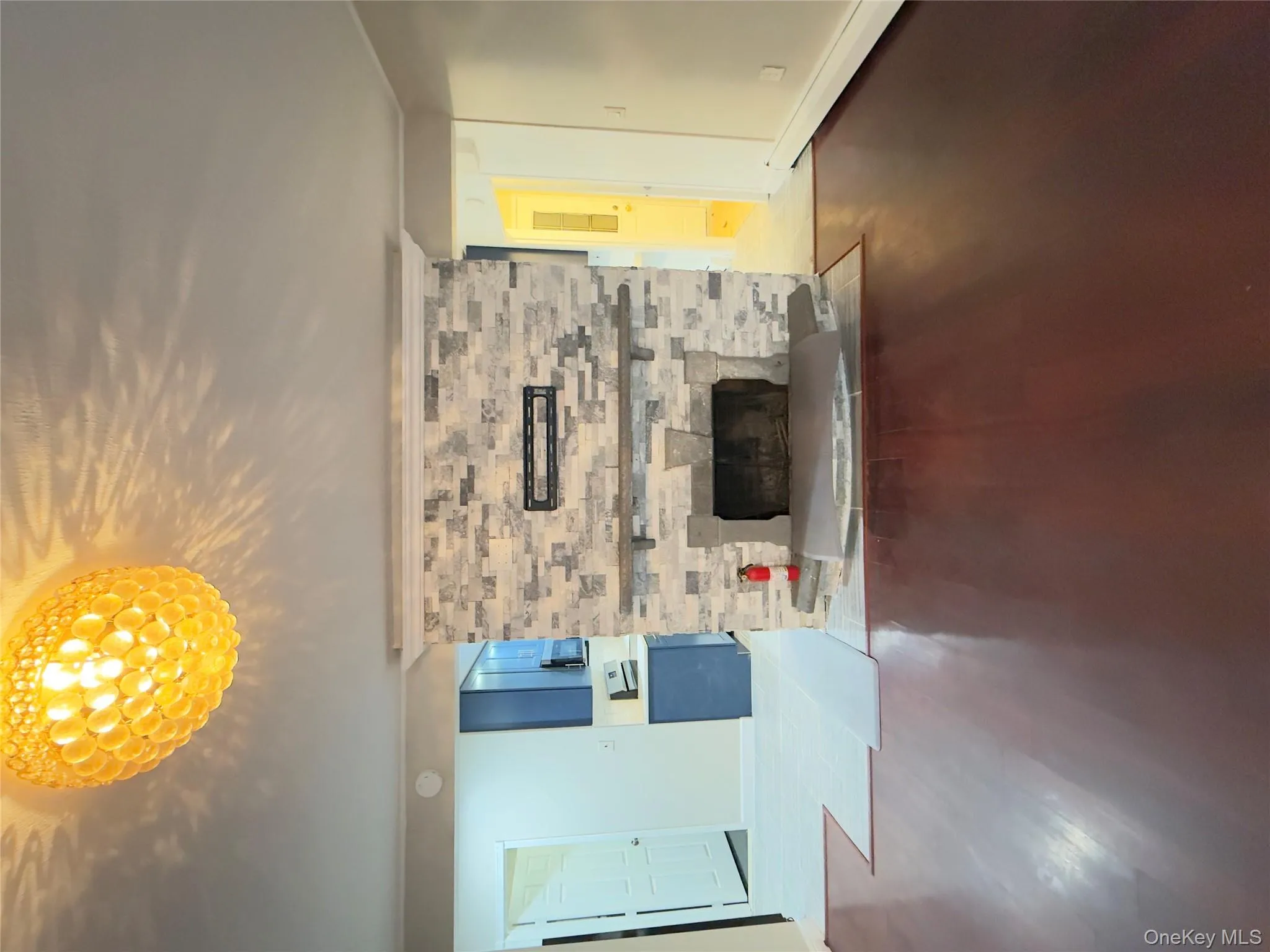 Unfurnished living room featuring baseboard heating, wood finished floors, a stone fireplace, and ornamental molding Unfurnished living room featuring baseboard heating, wood finished floors, a stone fireplace, and ornamental molding