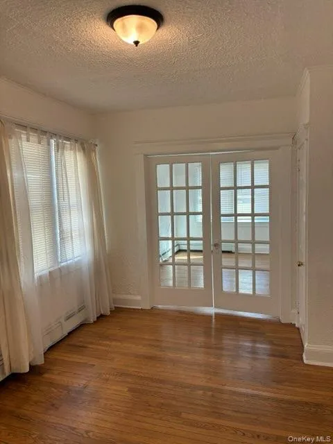 Empty room with french doors, a textured ceiling, and dark wood-type flooring Empty room with french doors, a textured ceiling, and dark wood-type flooring