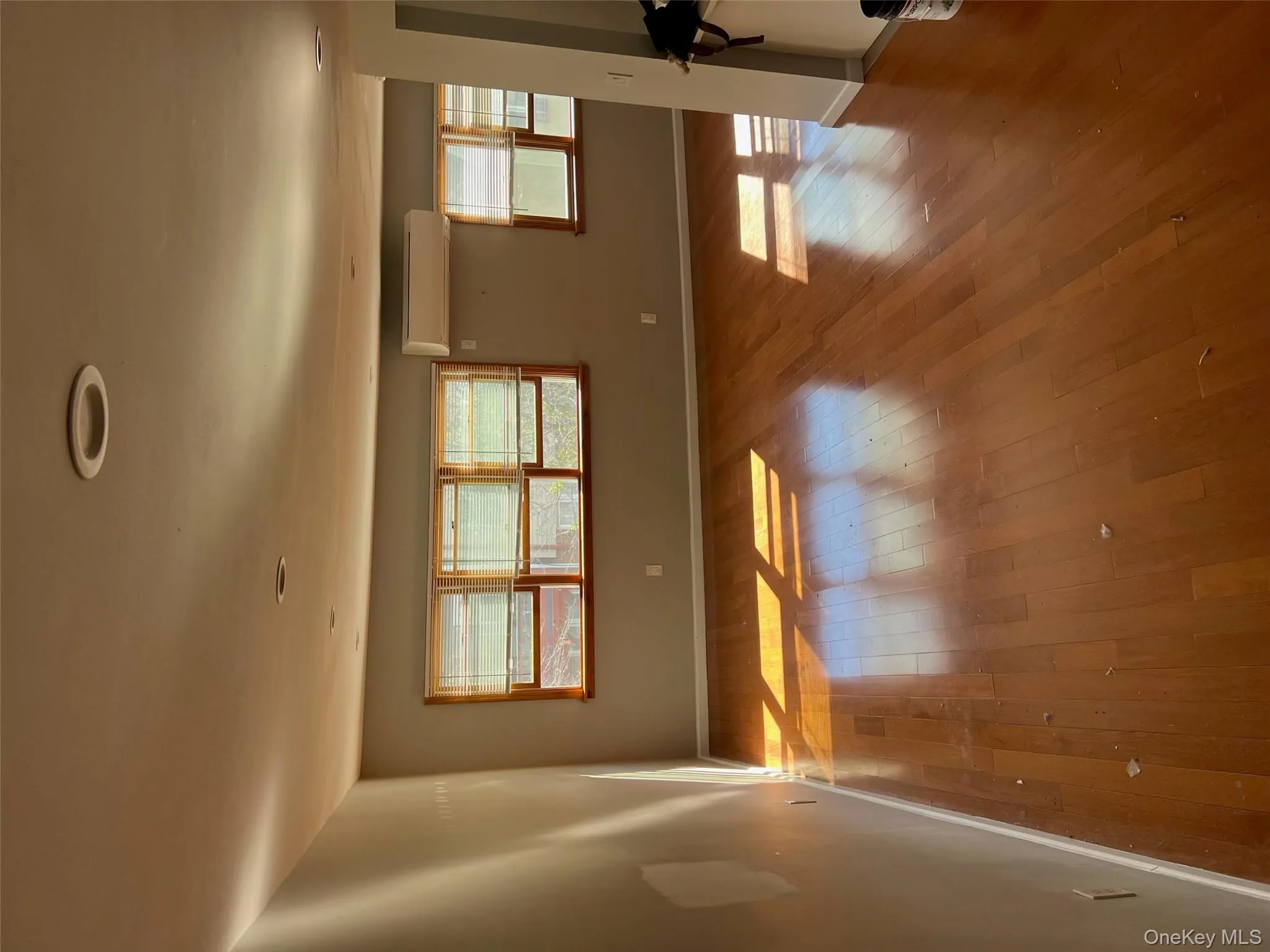Empty room with wood-type flooring, plenty of natural light, and an AC wall unit Empty room with wood-type flooring, plenty of natural light, and an AC wall unit