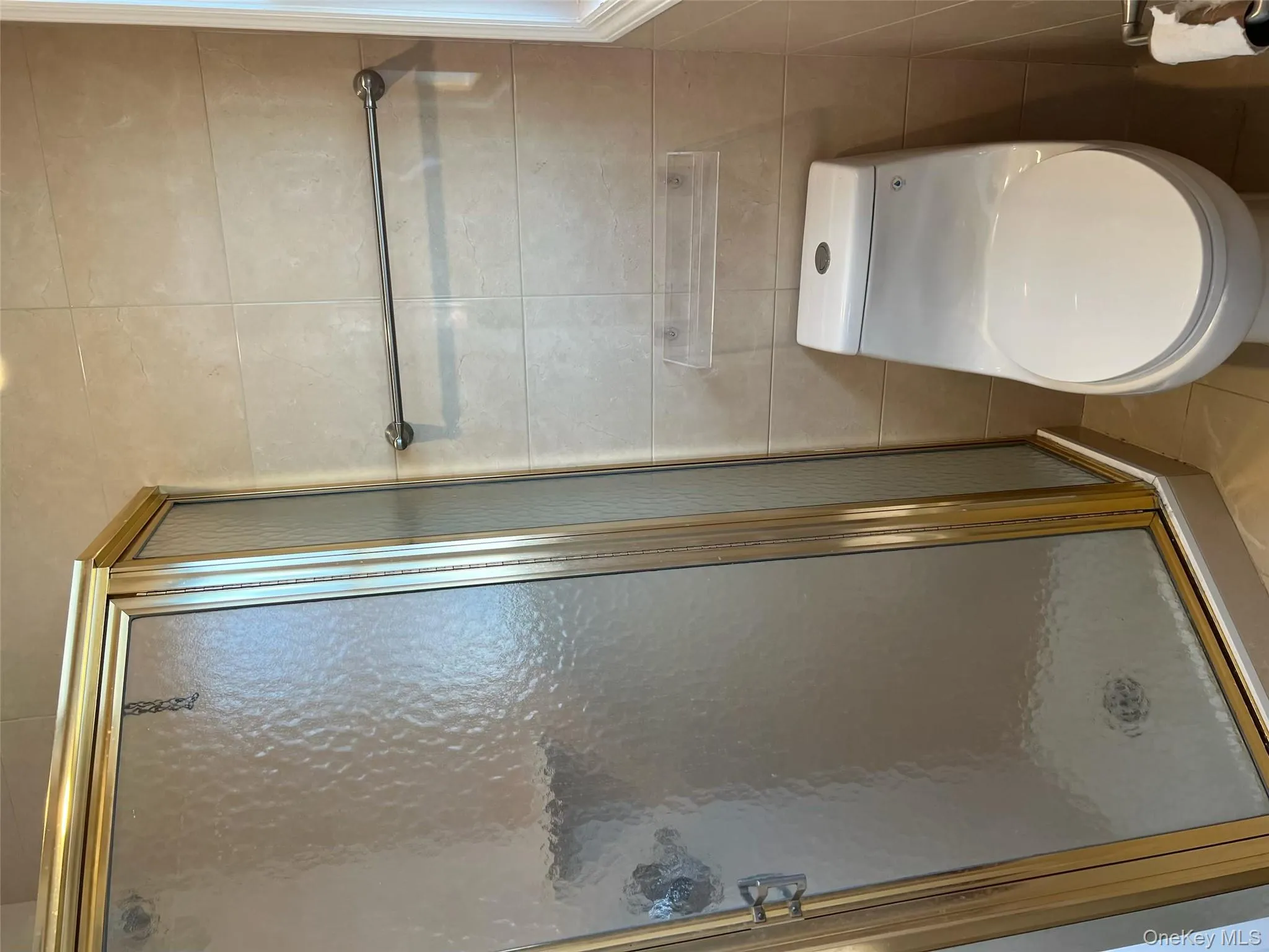 Bathroom featuring a stall shower, tile patterned floors, and tile walls Bathroom featuring a stall shower, tile patterned floors, and tile walls