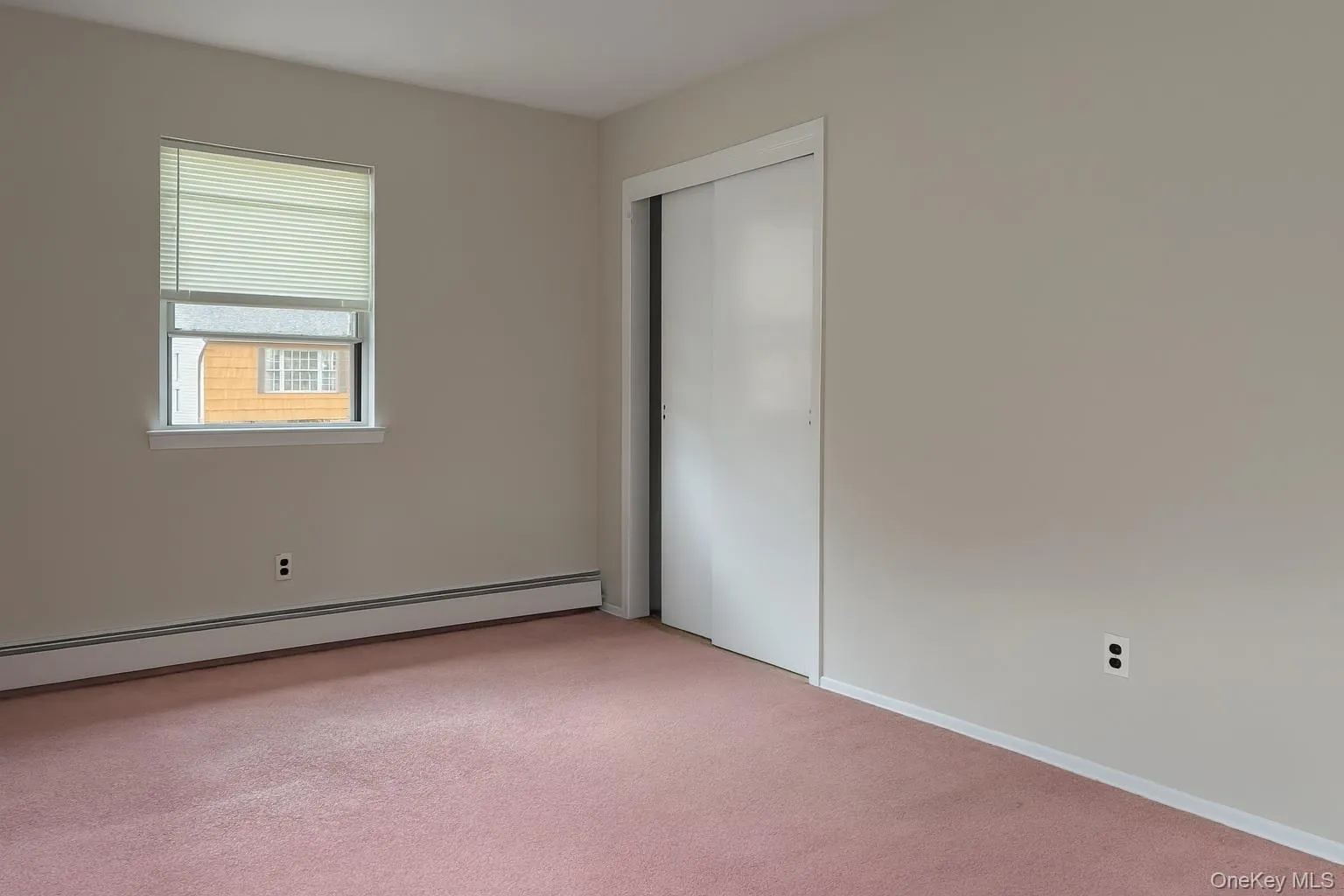Unfurnished bedroom featuring a baseboard radiator, carpet, and a closet Unfurnished bedroom featuring a baseboard radiator, carpet, and a closet