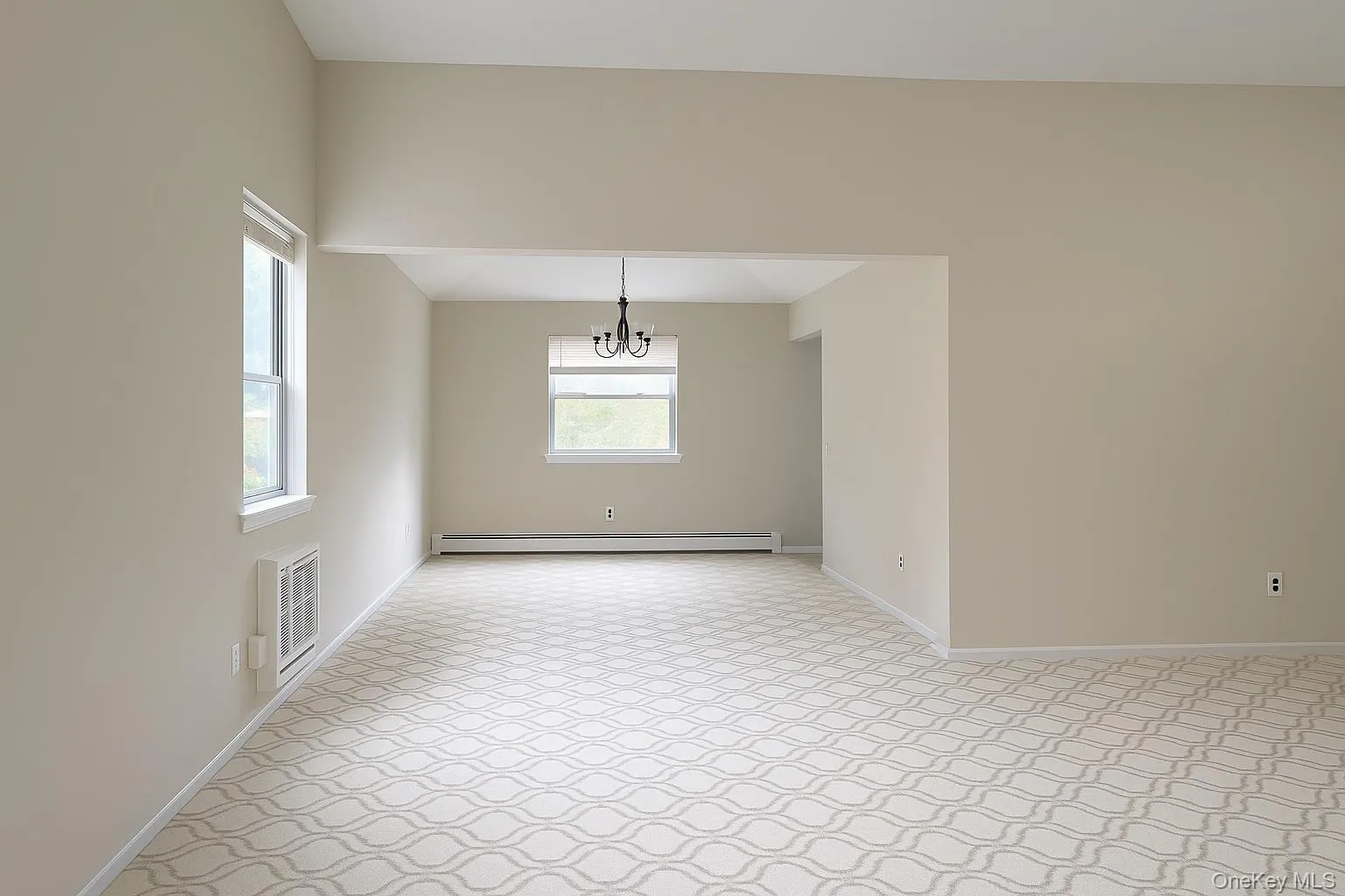 Unfurnished dining area featuring light carpet, a chandelier, and a baseboard radiator Unfurnished dining area featuring light carpet, a chandelier, and a baseboard radiator