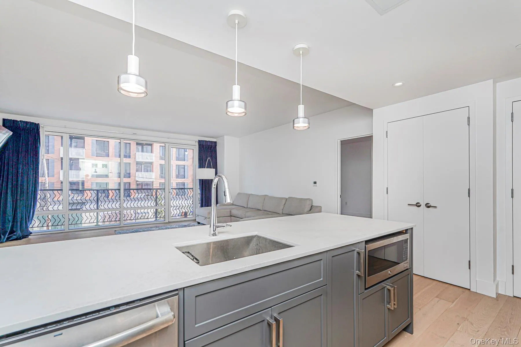 Kitchen with light stone countertops, gray cabinetry, appliances with stainless steel finishes, light wood-type flooring, and recessed lighting Kitchen with light stone countertops, gray cabinetry, appliances with stainless steel finishes, light wood-type flooring, and recessed lighting