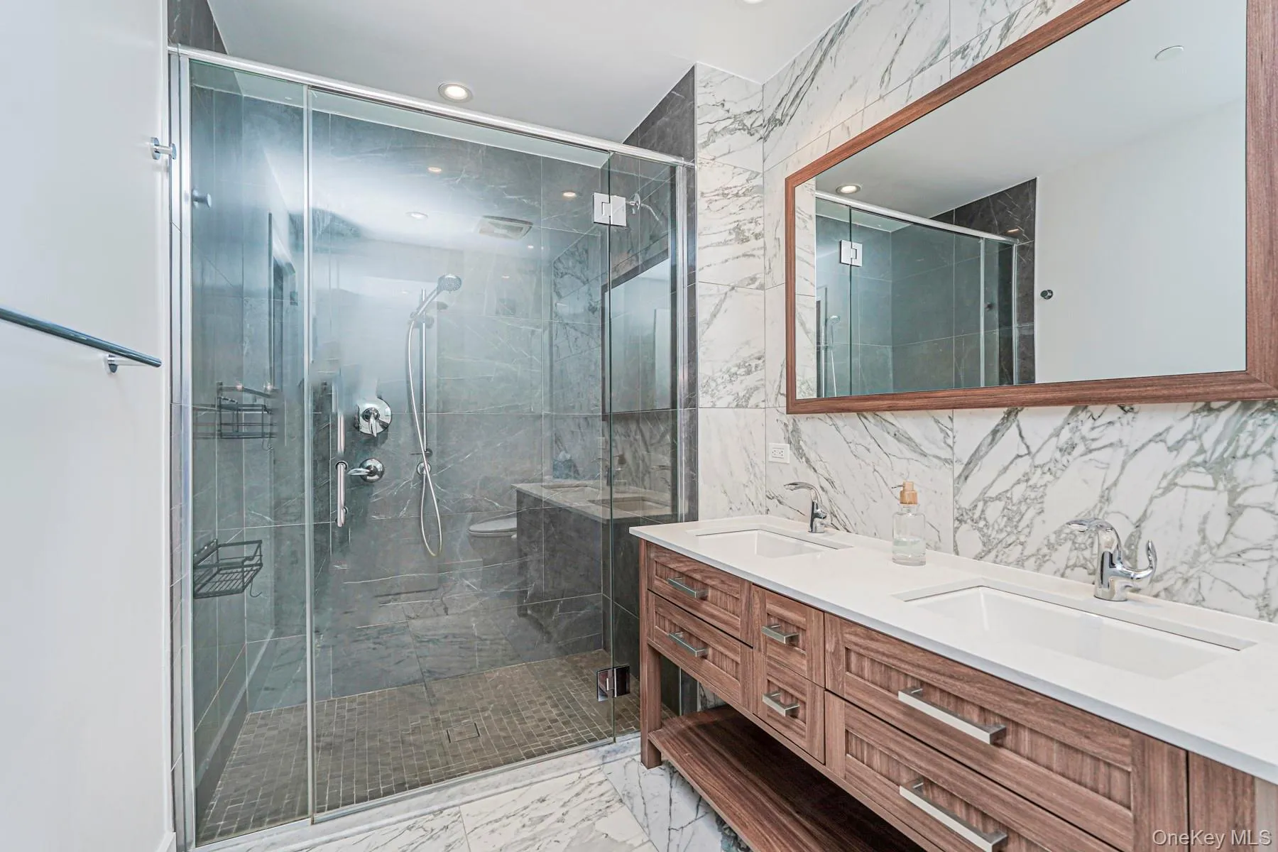 Full bathroom with double vanity, tile walls, a stall shower, recessed lighting, and light marble finish flooring Full bathroom with double vanity, tile walls, a stall shower, recessed lighting, and light marble finish flooring