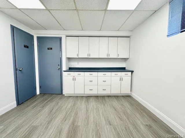 Kitchen featuring white cabinets, a drop ceiling, and light wood-type flooring Kitchen featuring white cabinets, a drop ceiling, and light wood-type flooring
