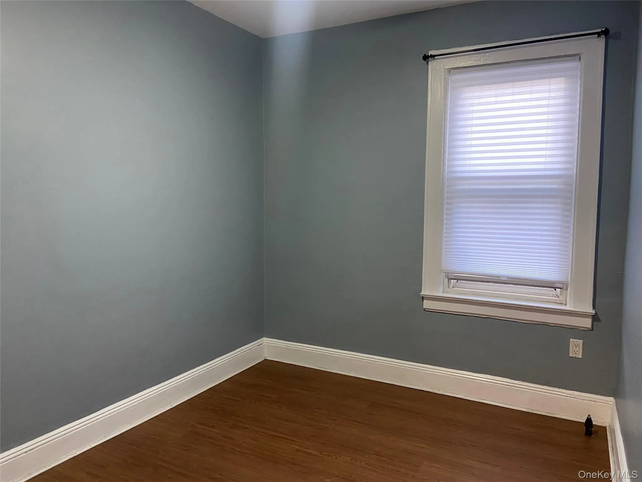 Unfurnished room with baseboards and dark wood-type flooring Unfurnished room with baseboards and dark wood-type flooring
