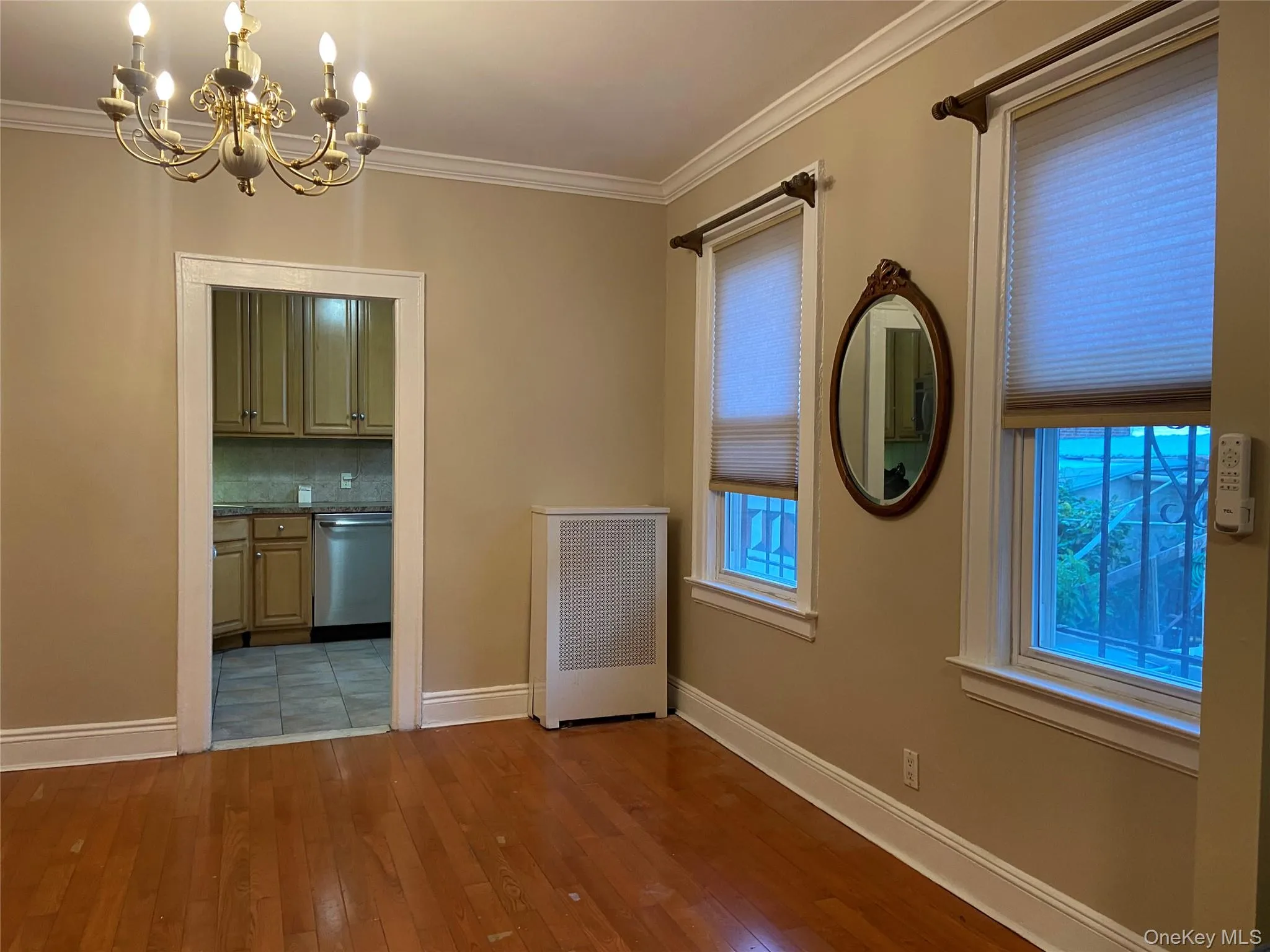Unfurnished dining area with crown molding, a chandelier, radiator, and dark wood-style floors Unfurnished dining area with crown molding, a chandelier, radiator, and dark wood-style floors