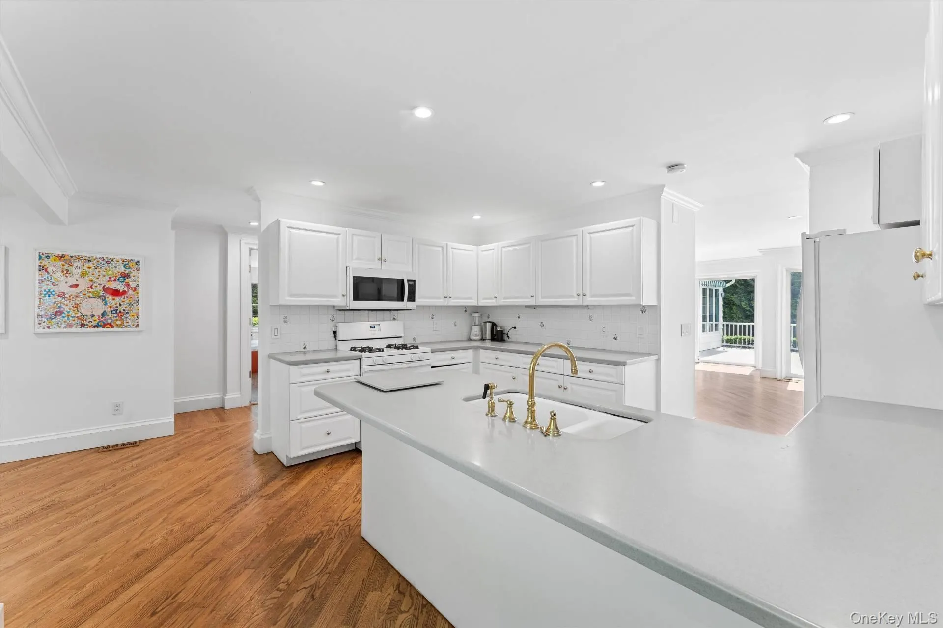 Kitchen featuring white cabinets, light wood-style flooring, white appliances, tasteful backsplash, and recessed lighting Kitchen featuring white cabinets, light wood-style flooring, white appliances, tasteful backsplash, and recessed lighting