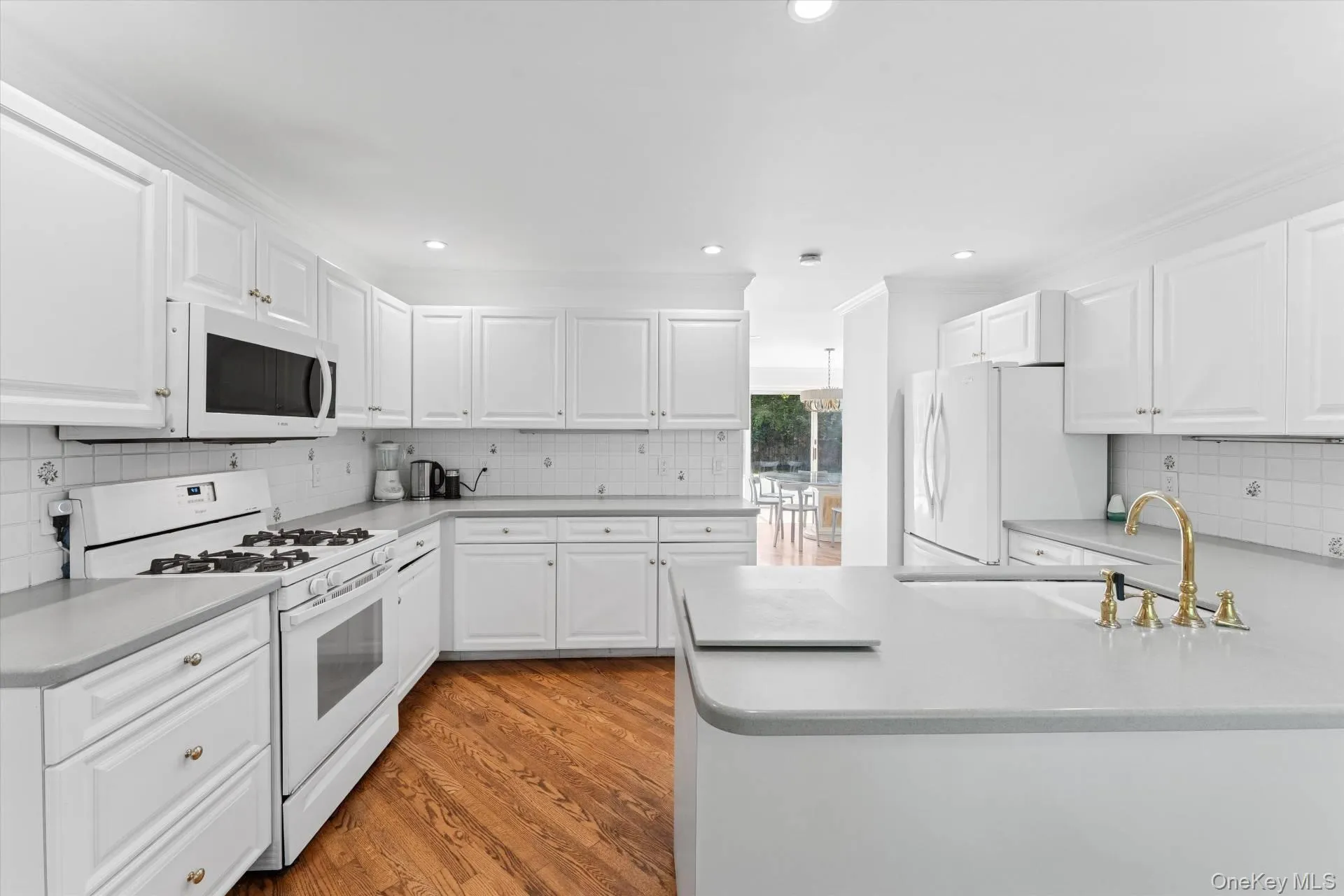 Kitchen featuring white appliances, white cabinets, decorative backsplash, light wood-type flooring, and recessed lighting Kitchen featuring white appliances, white cabinets, decorative backsplash, light wood-type flooring, and recessed lighting