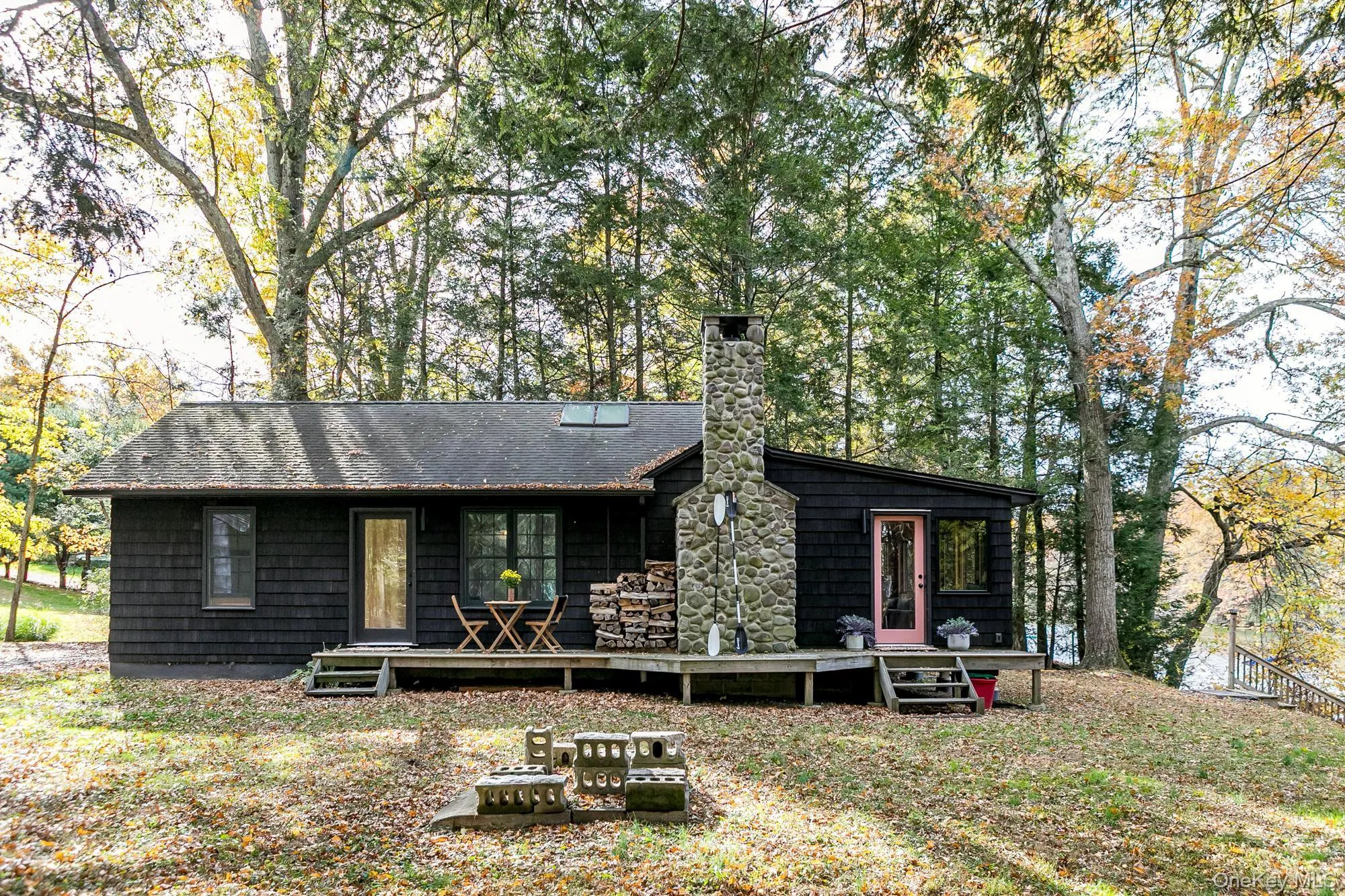 Back of house featuring a chimney, a deck, and view of scattered trees Back of house featuring a chimney, a deck, and view of scattered trees