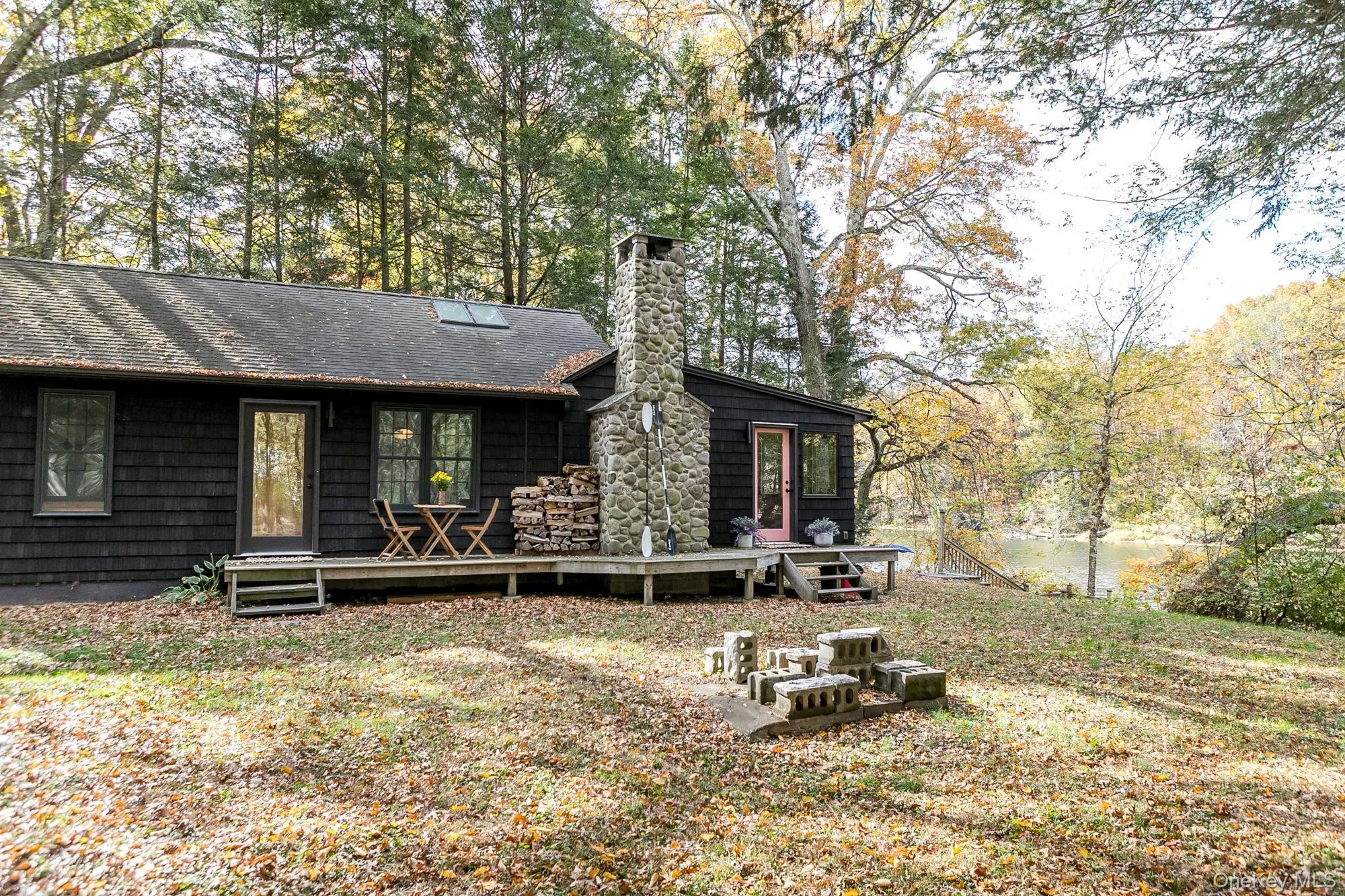 Back of house with a chimney, a wooden deck, and view of wooded area Back of house with a chimney, a wooden deck, and view of wooded area