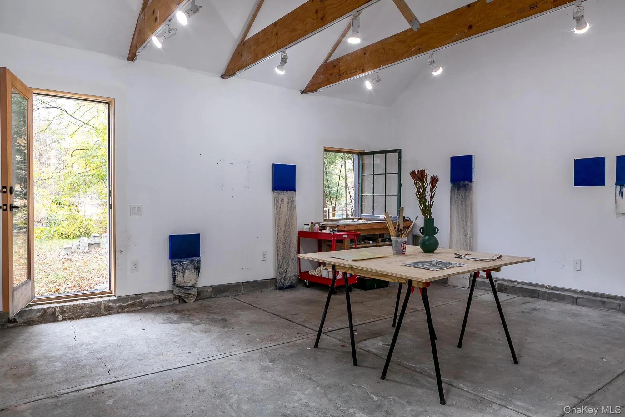 Dining area featuring beam ceiling, concrete floors, high vaulted ceiling, and track lighting Dining area featuring beam ceiling, concrete floors, high vaulted ceiling, and track lighting