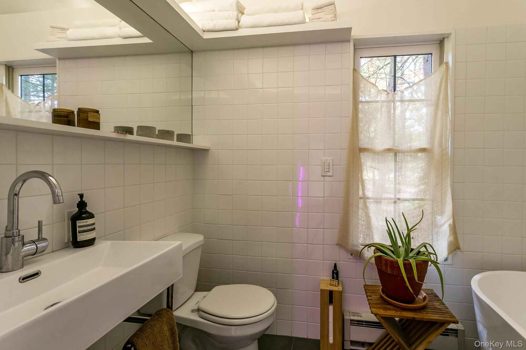 Bathroom with tile walls, a freestanding bath, and a baseboard radiator Bathroom with tile walls, a freestanding bath, and a baseboard radiator