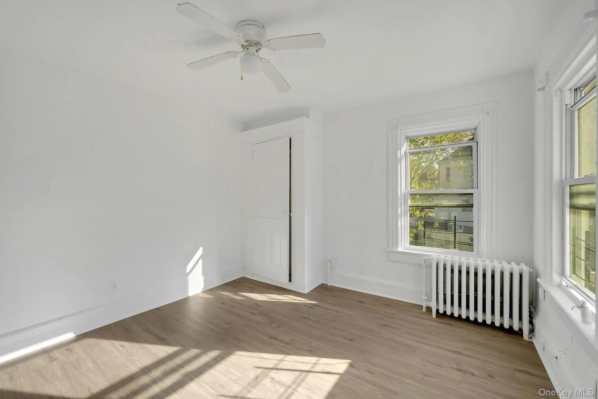 Spare room with radiator heating unit, light wood-type flooring, and ceiling fan Spare room with radiator heating unit, light wood-type flooring, and ceiling fan