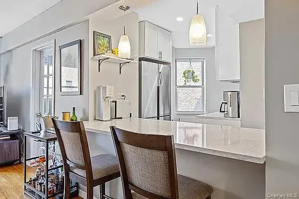 Kitchen featuring white cabinets, a kitchen bar, built in fridge, and recessed lighting Kitchen featuring white cabinets, a kitchen bar, built in fridge, and recessed lighting