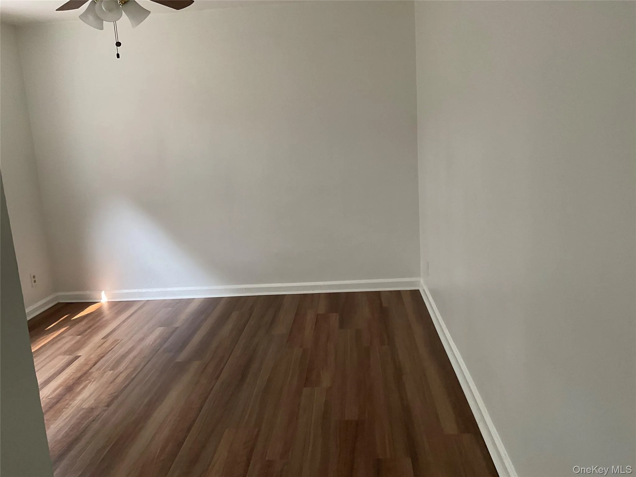 Spare room with dark wood-type flooring and ceiling fan Spare room with dark wood-type flooring and ceiling fan