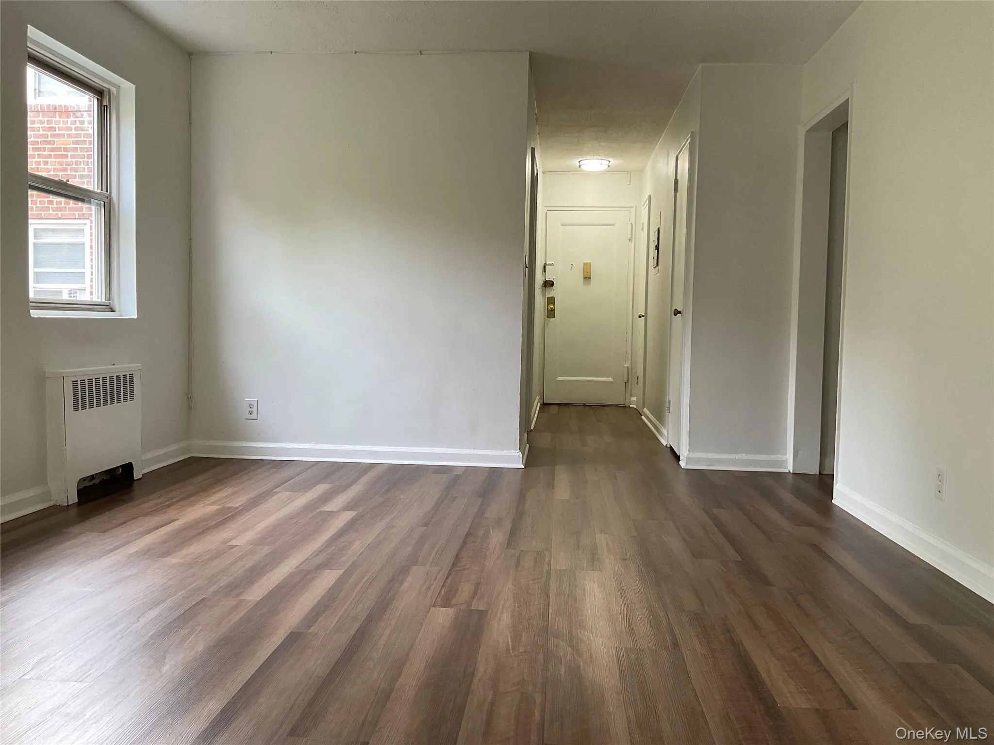 Unfurnished room featuring dark wood-style flooring and radiator heating unit Unfurnished room featuring dark wood-style flooring and radiator heating unit