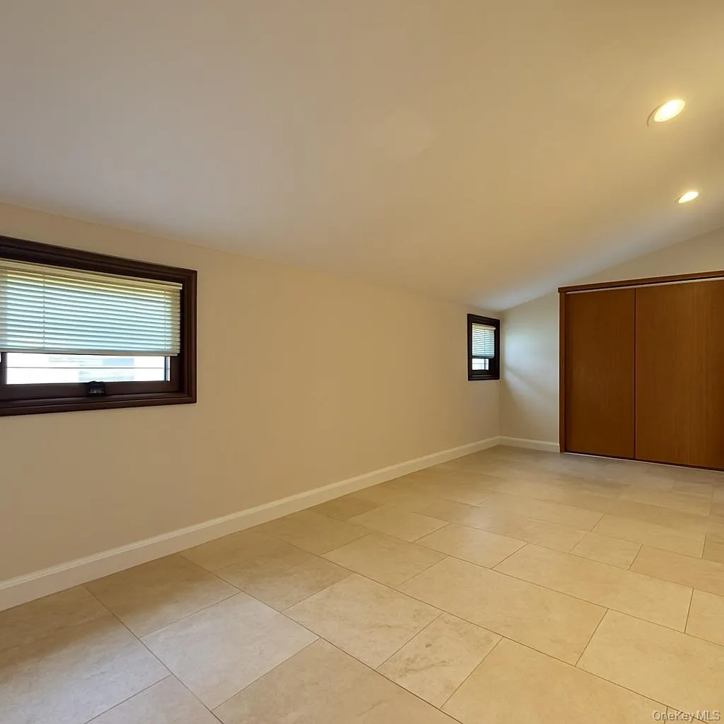 Unfurnished bedroom featuring recessed lighting, vaulted ceiling, light tile patterned floors, and a closet Unfurnished bedroom featuring recessed lighting, vaulted ceiling, light tile patterned floors, and a closet
