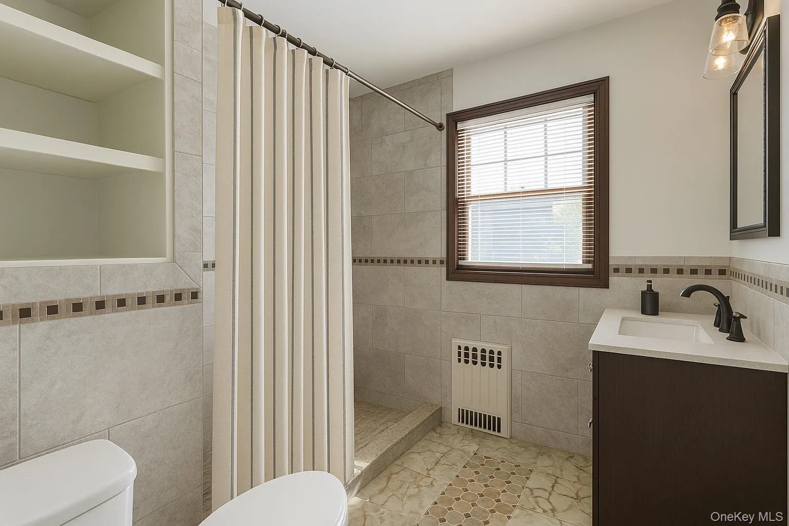 Bathroom with vanity, tile walls, radiator heating unit, and a shower stall Bathroom with vanity, tile walls, radiator heating unit, and a shower stall