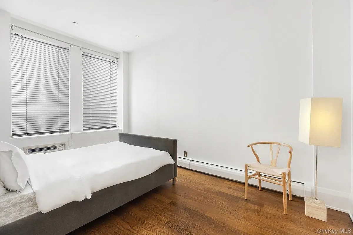Bedroom featuring wood finished floors and a baseboard heating unit Bedroom featuring wood finished floors and a baseboard heating unit