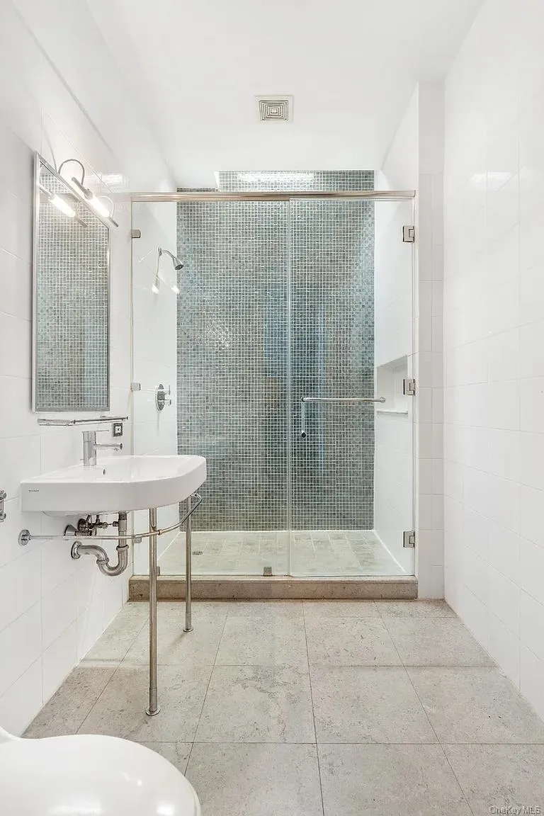 Full bathroom with a stall shower, tile walls, and tile patterned floors Full bathroom with a stall shower, tile walls, and tile patterned floors