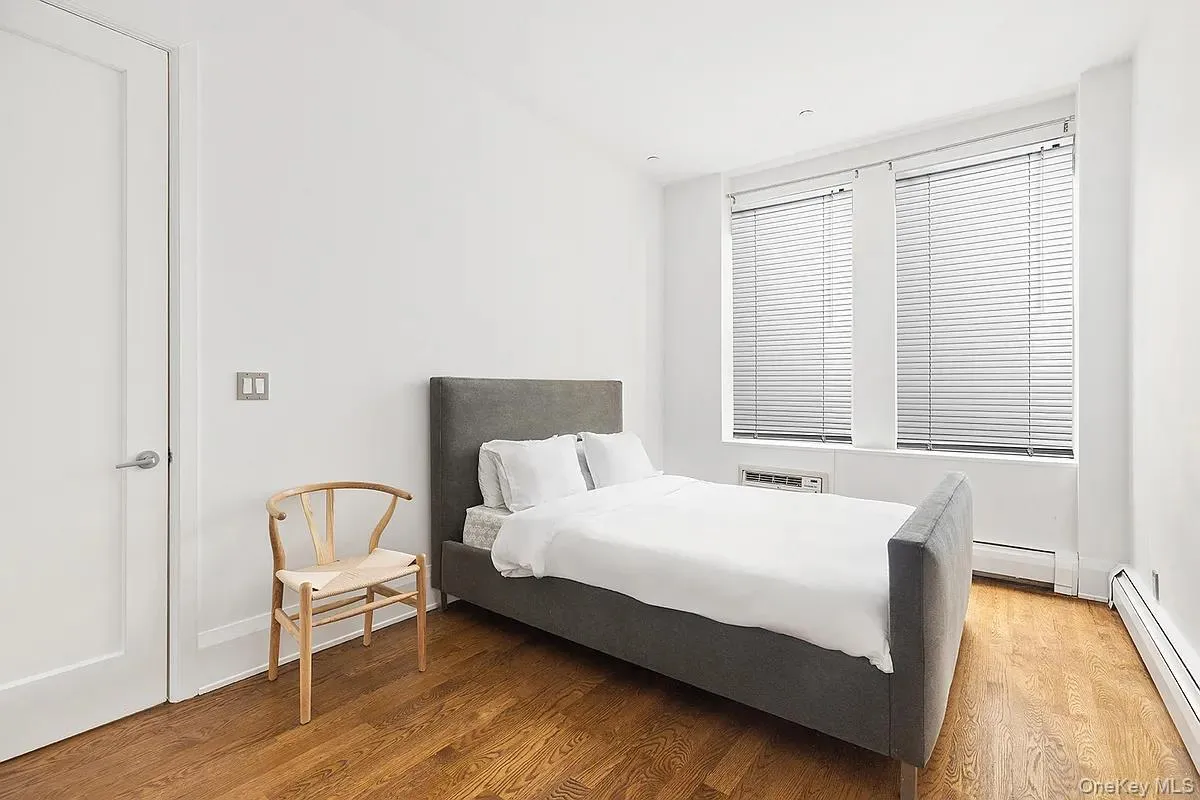 Bedroom with baseboard heating, wood finished floors, and a baseboard radiator Bedroom with baseboard heating, wood finished floors, and a baseboard radiator