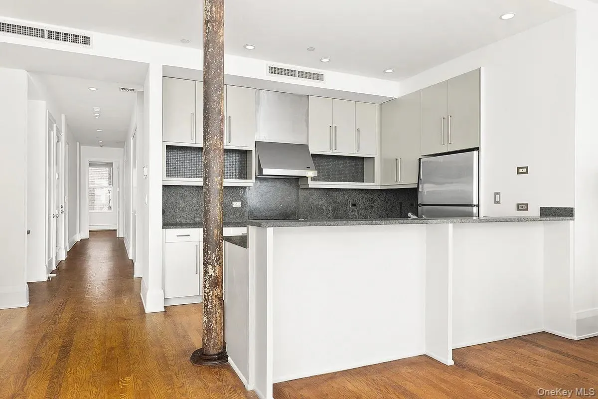 Kitchen with freestanding refrigerator, dark wood-type flooring, recessed lighting, tasteful backsplash, and wall chimney exhaust hood Kitchen with freestanding refrigerator, dark wood-type flooring, recessed lighting, tasteful backsplash, and wall chimney exhaust hood