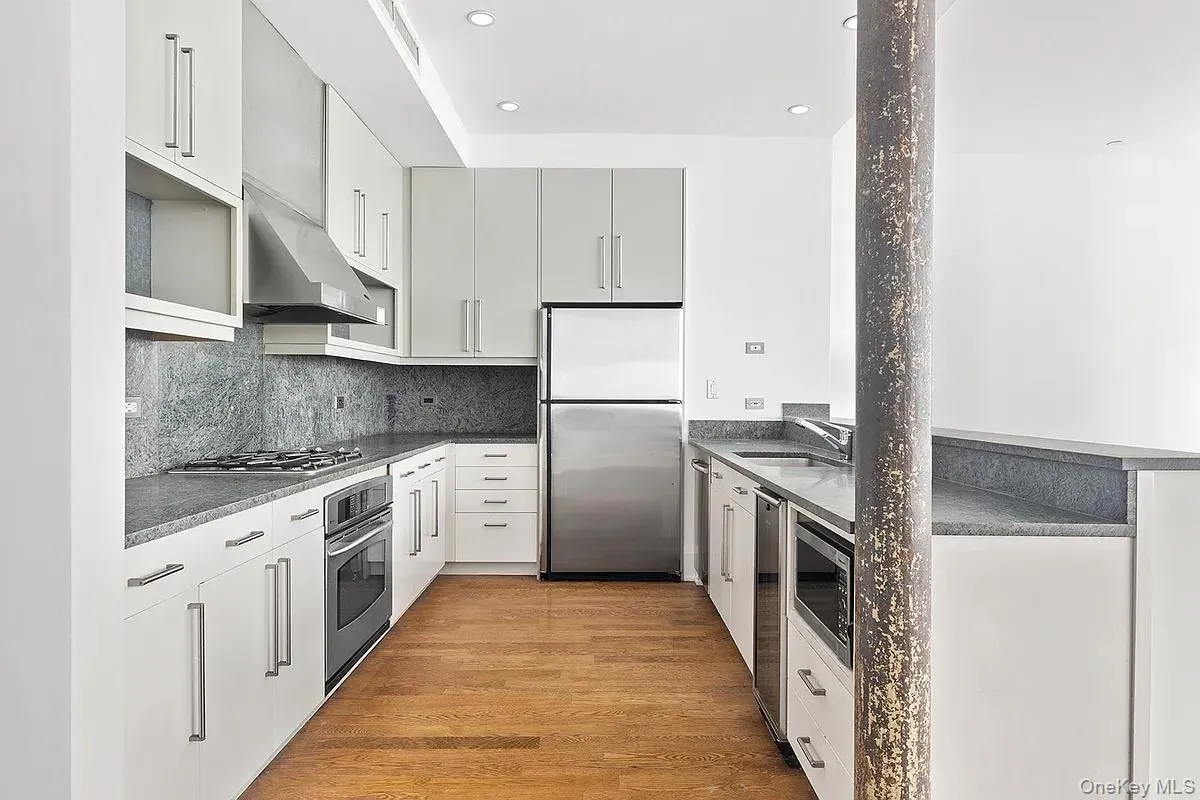 Kitchen featuring appliances with stainless steel finishes, under cabinet range hood, light wood-style flooring, decorative backsplash, and recessed lighting Kitchen featuring appliances with stainless steel finishes, under cabinet range hood, light wood-style flooring, decorative backsplash, and recessed lighting