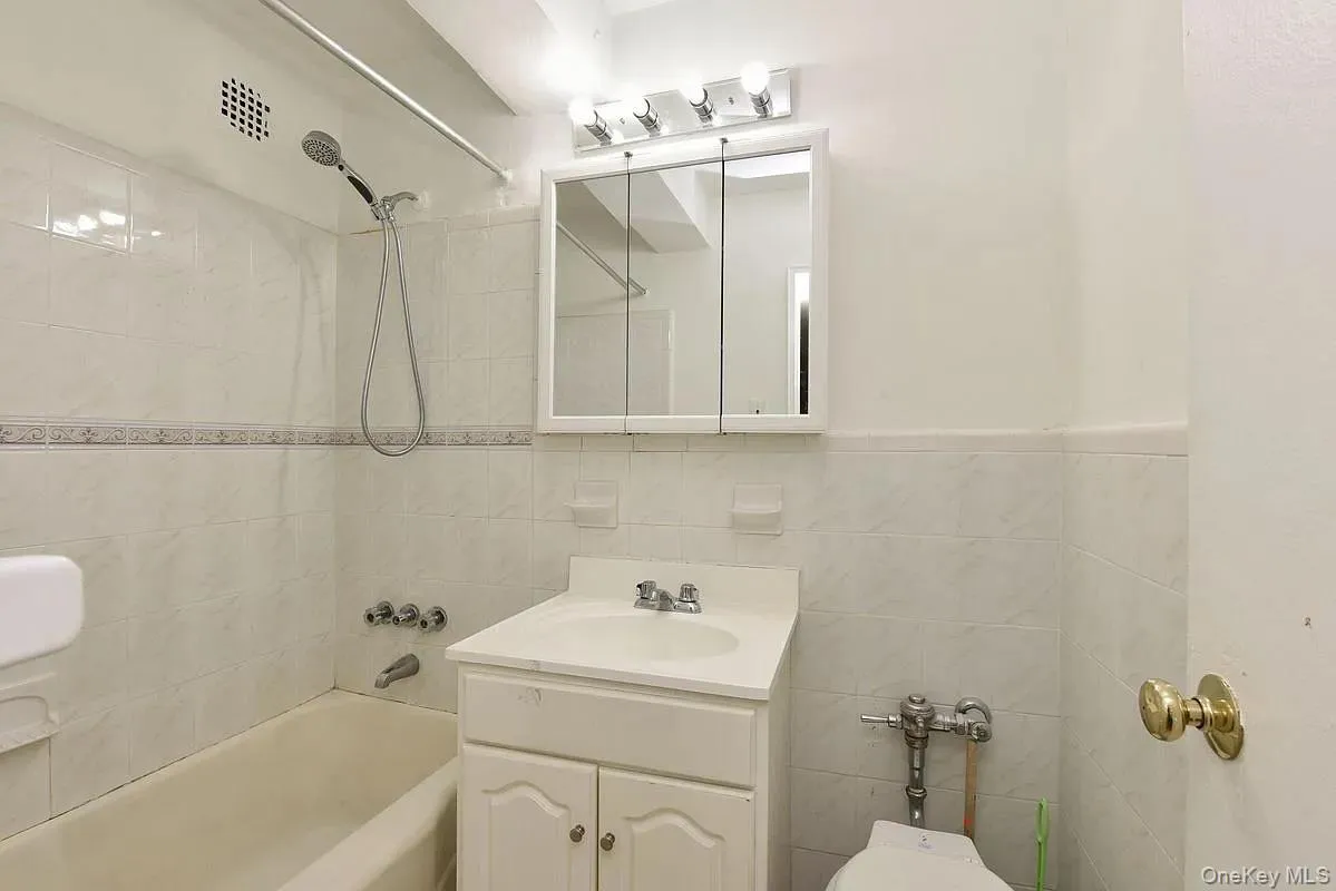 Bathroom featuring vanity, shower / tub combination, and tile walls Bathroom featuring vanity, shower / tub combination, and tile walls
