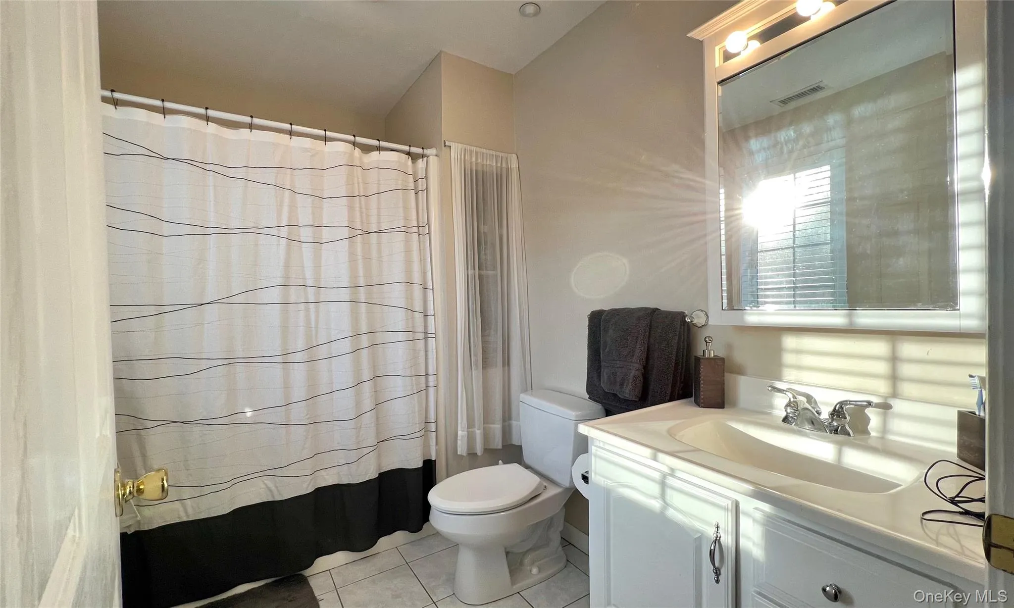 Bathroom with light tile patterned floors, a shower with curtain, and vanity Bathroom with light tile patterned floors, a shower with curtain, and vanity