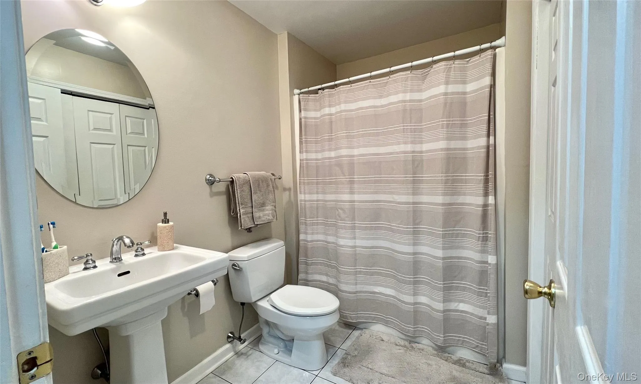 Full bathroom featuring a shower with curtain and light tile patterned flooring Full bathroom featuring a shower with curtain and light tile patterned flooring