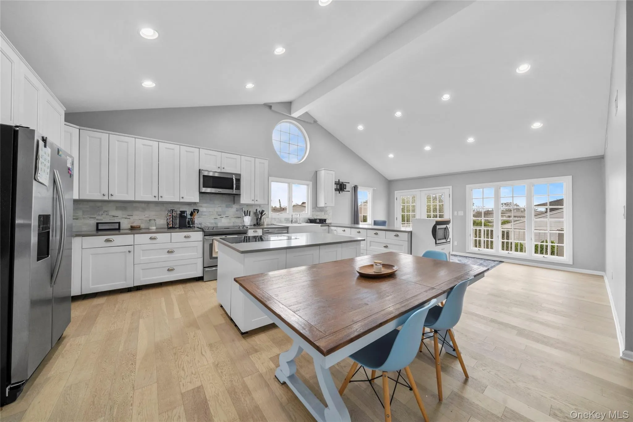 Kitchen with a peninsula, a center island, white cabinetry, stainless steel appliances, and backsplash Kitchen with a peninsula, a center island, white cabinetry, stainless steel appliances, and backsplash