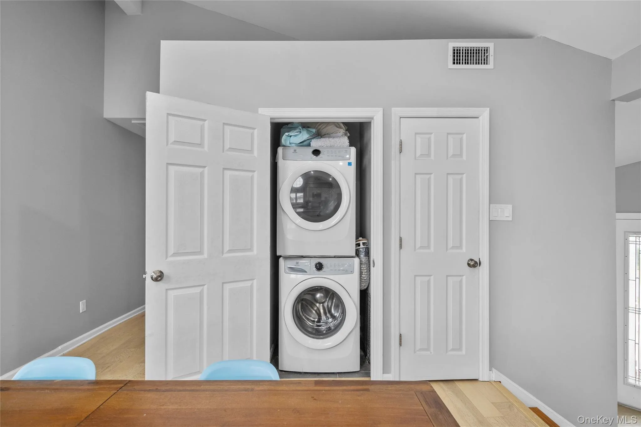 Laundry area featuring stacked washer / dryer and wood finished floors Laundry area featuring stacked washer / dryer and wood finished floors