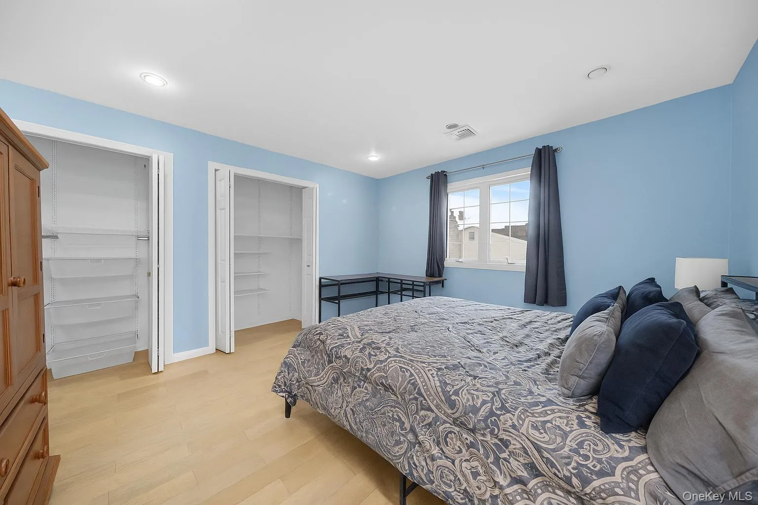 Bedroom with multiple closets, light wood finished floors, and recessed lighting Bedroom with multiple closets, light wood finished floors, and recessed lighting