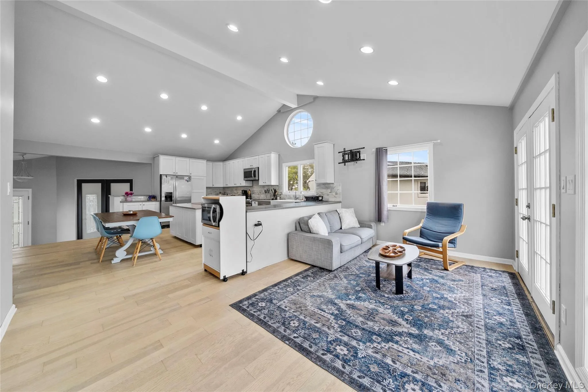 Living area with light wood finished floors, beamed ceiling, high vaulted ceiling, recessed lighting, and french doors Living area with light wood finished floors, beamed ceiling, high vaulted ceiling, recessed lighting, and french doors