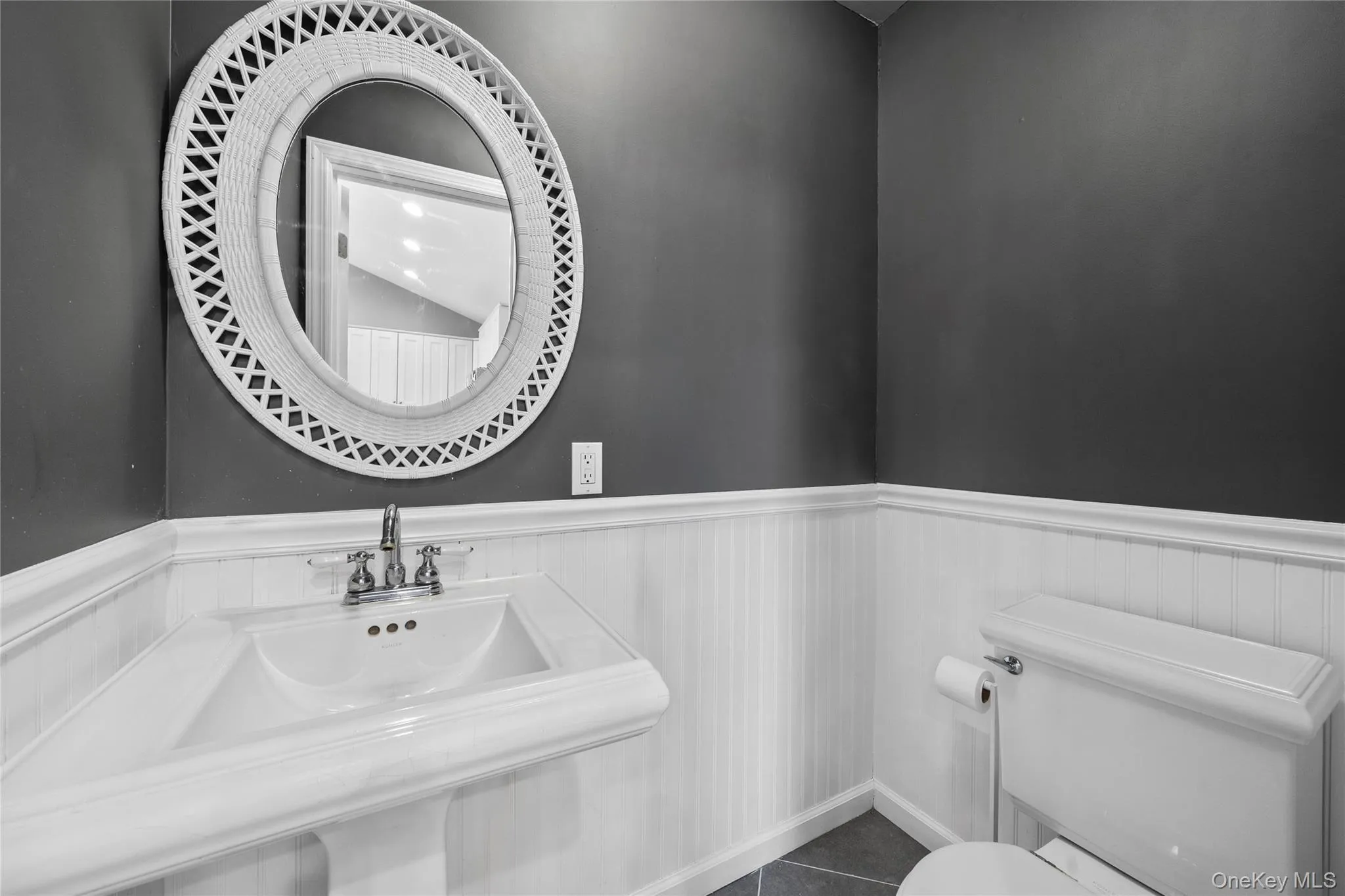 Bathroom featuring a wainscoted wall and dark tile patterned floors Bathroom featuring a wainscoted wall and dark tile patterned floors