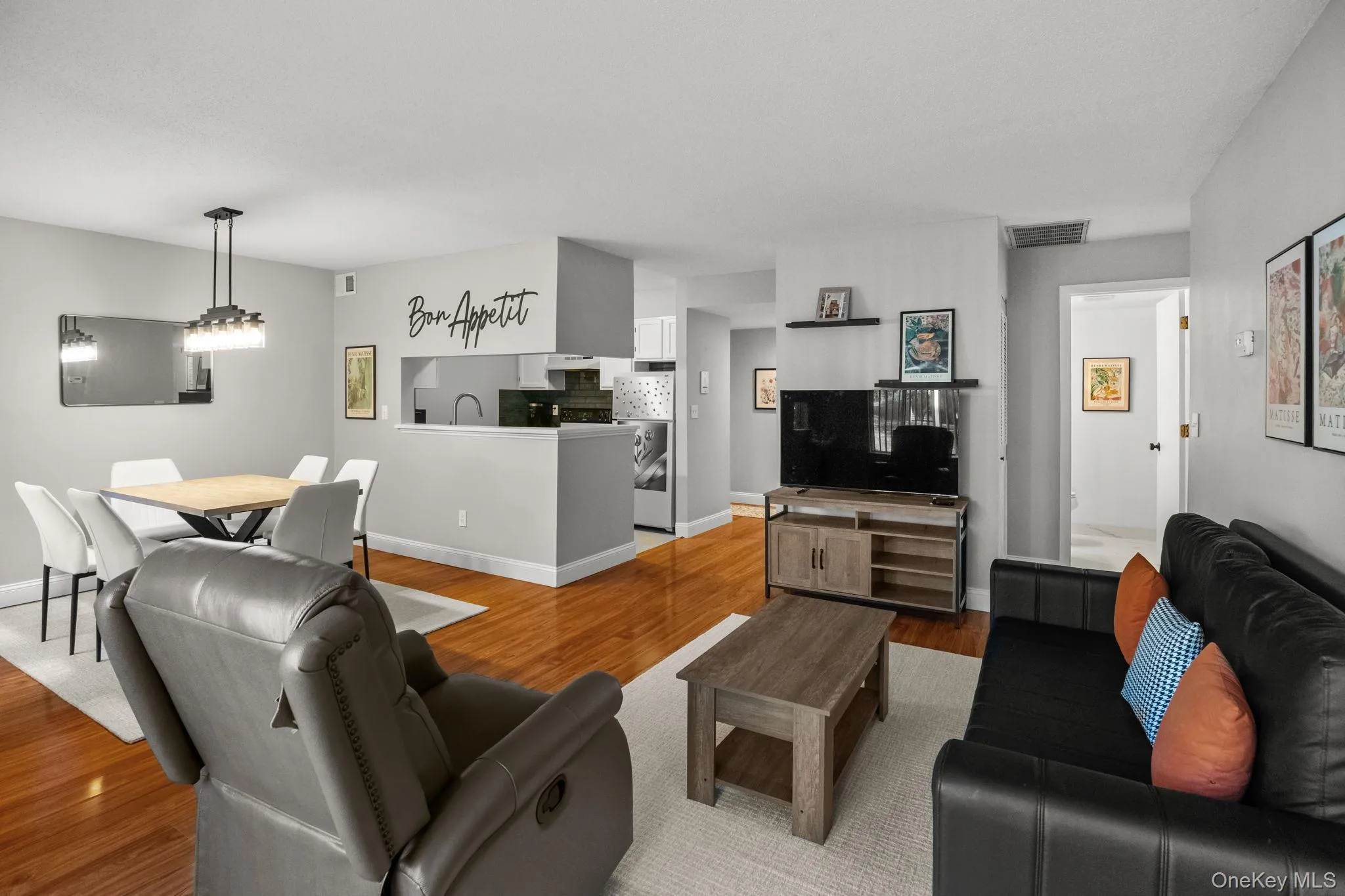 Bright and inviting open-concept living and dining area featuring gleaming hardwood floors, modern lighting, and a seamless flow to the kitchen. Bright and inviting open-concept living and dining area featuring gleaming hardwood floors, modern lighting, and a seamless flow to the kitchen.