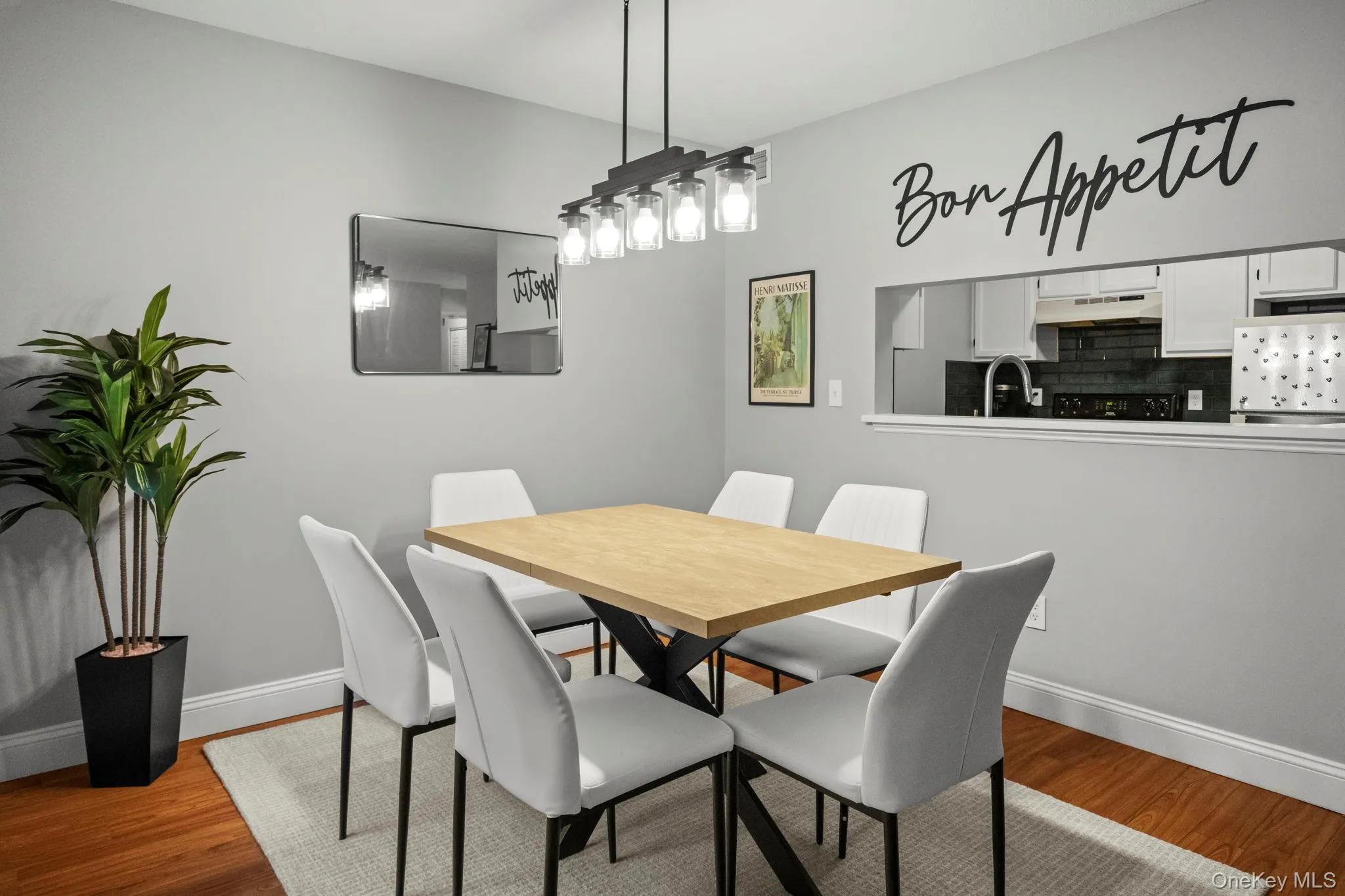A sleek chandelier and neutral palette enhance the open layout, offering a comfortable flow between the dining area and kitchen. A sleek chandelier and neutral palette enhance the open layout, offering a comfortable flow between the dining area and kitchen.