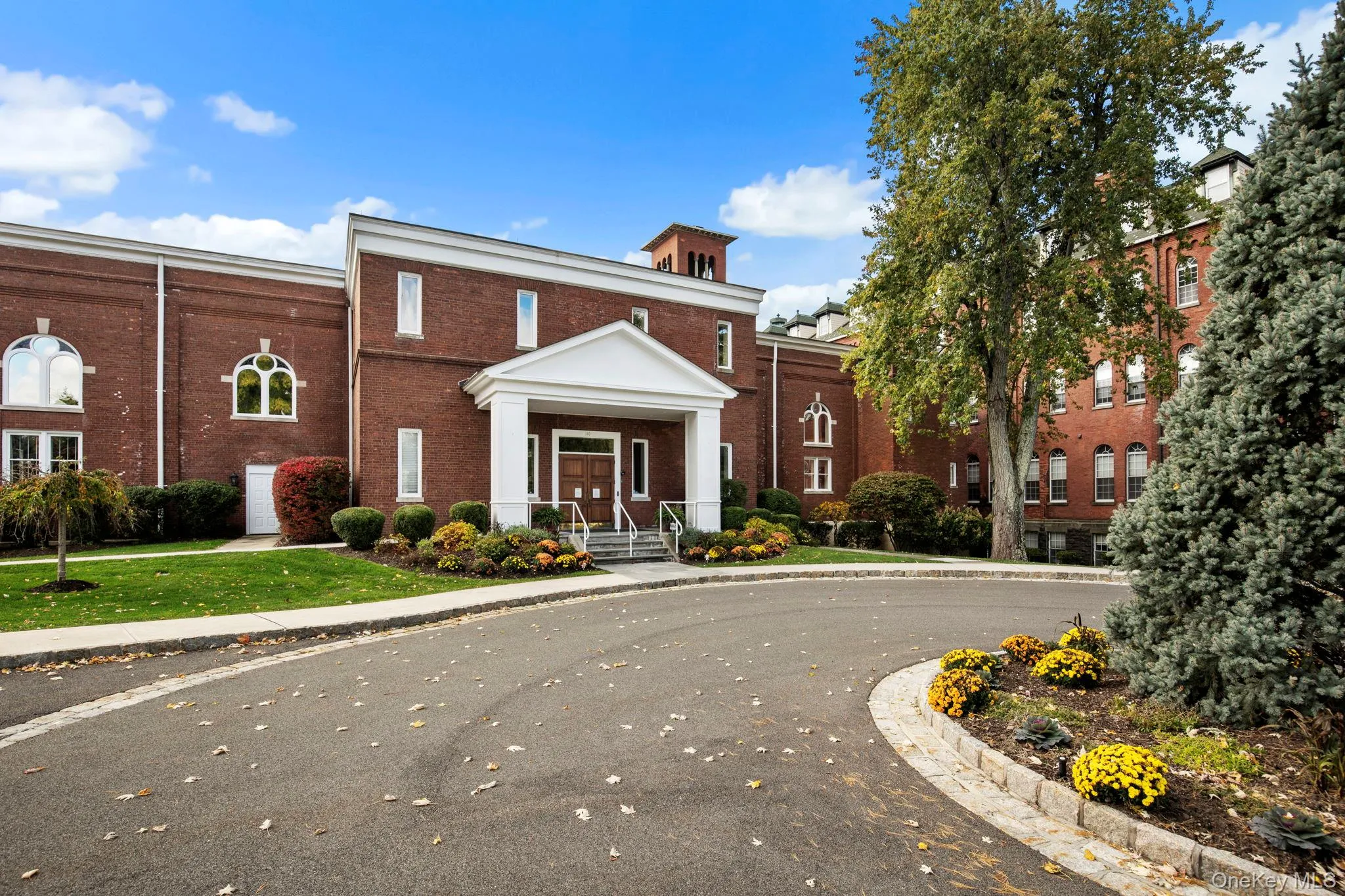 Rear view of the stately brick clubhouse surrounded by manicured landscaping and walkways leading to community amenities. Rear view of the stately brick clubhouse surrounded by manicured landscaping and walkways leading to community amenities.