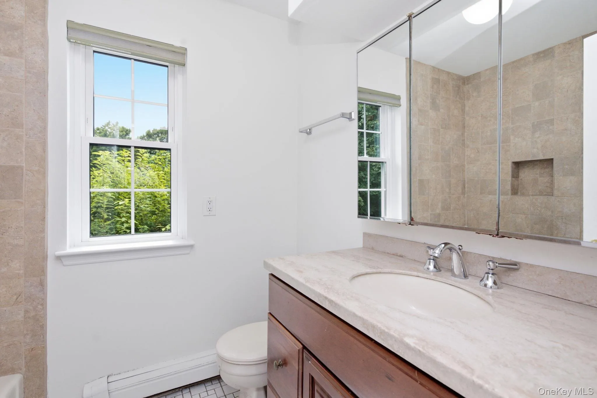 The full bath features a tiled walk-in shower with a built-in niche, marble-style vanity top, wood vanity, large mirror cabinet, and two windows that keep the space naturally bright. The full bath features a tiled walk-in shower with a built-in niche, marble-style vanity top, wood vanity, large mirror cabinet, and two windows that keep the space naturally bright.