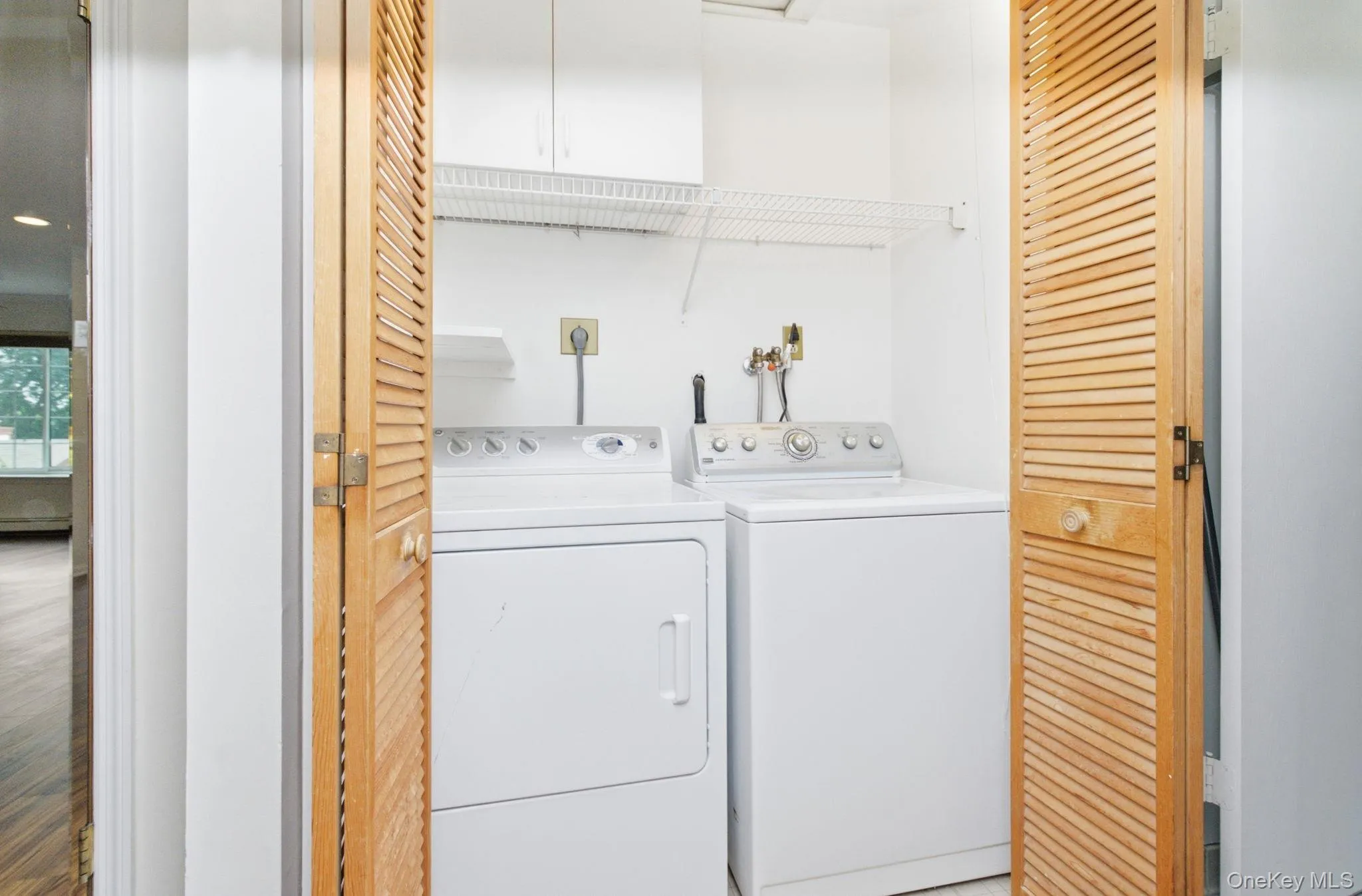 Full-size washer and dryer sit neatly behind louvered doors with overhead cabinetry and additional wire shelving, giving you in-unit laundry convenience without sacrificing any living space. Full-size washer and dryer sit neatly behind louvered doors with overhead cabinetry and additional wire shelving, giving you in-unit laundry convenience without sacrificing any living space.