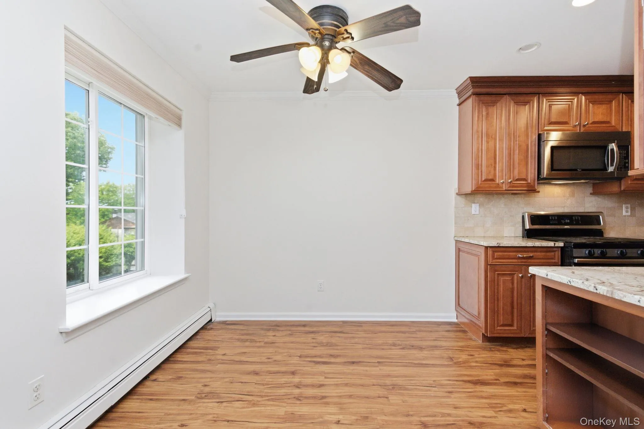 The dining nook sits just off the kitchen with a picture window framing a blue sky view, a ceiling fan, and wide-plank flooring making it a bright everyday spot that gets great morning light. The dining nook sits just off the kitchen with a picture window framing a blue sky view, a ceiling fan, and wide-plank flooring making it a bright everyday spot that gets great morning light.