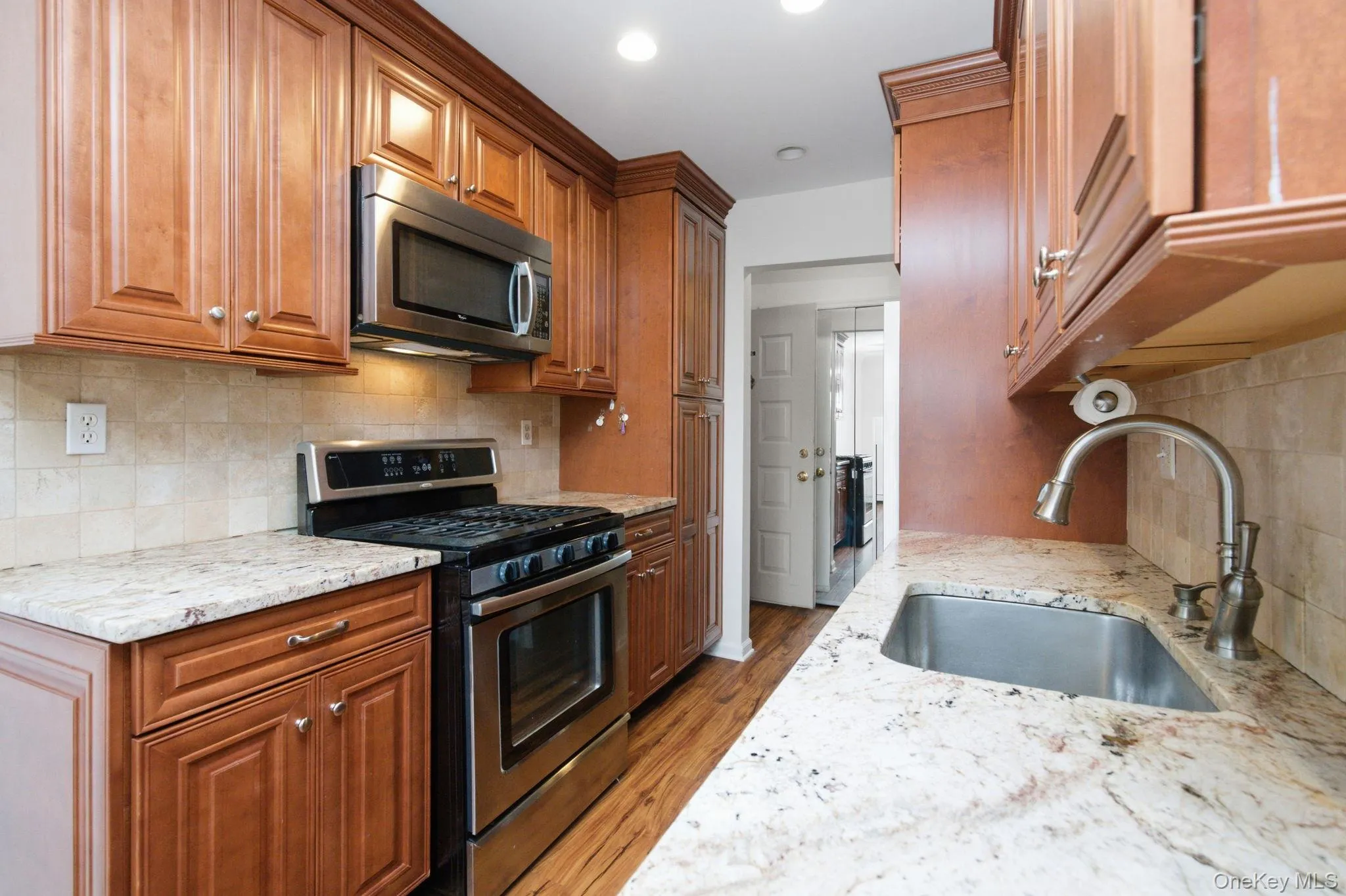 A second angle of the kitchen highlights the deep undermount sink, brushed nickel faucet, and the open passage leading directly into the dining space beyond. A second angle of the kitchen highlights the deep undermount sink, brushed nickel faucet, and the open passage leading directly into the dining space beyond.