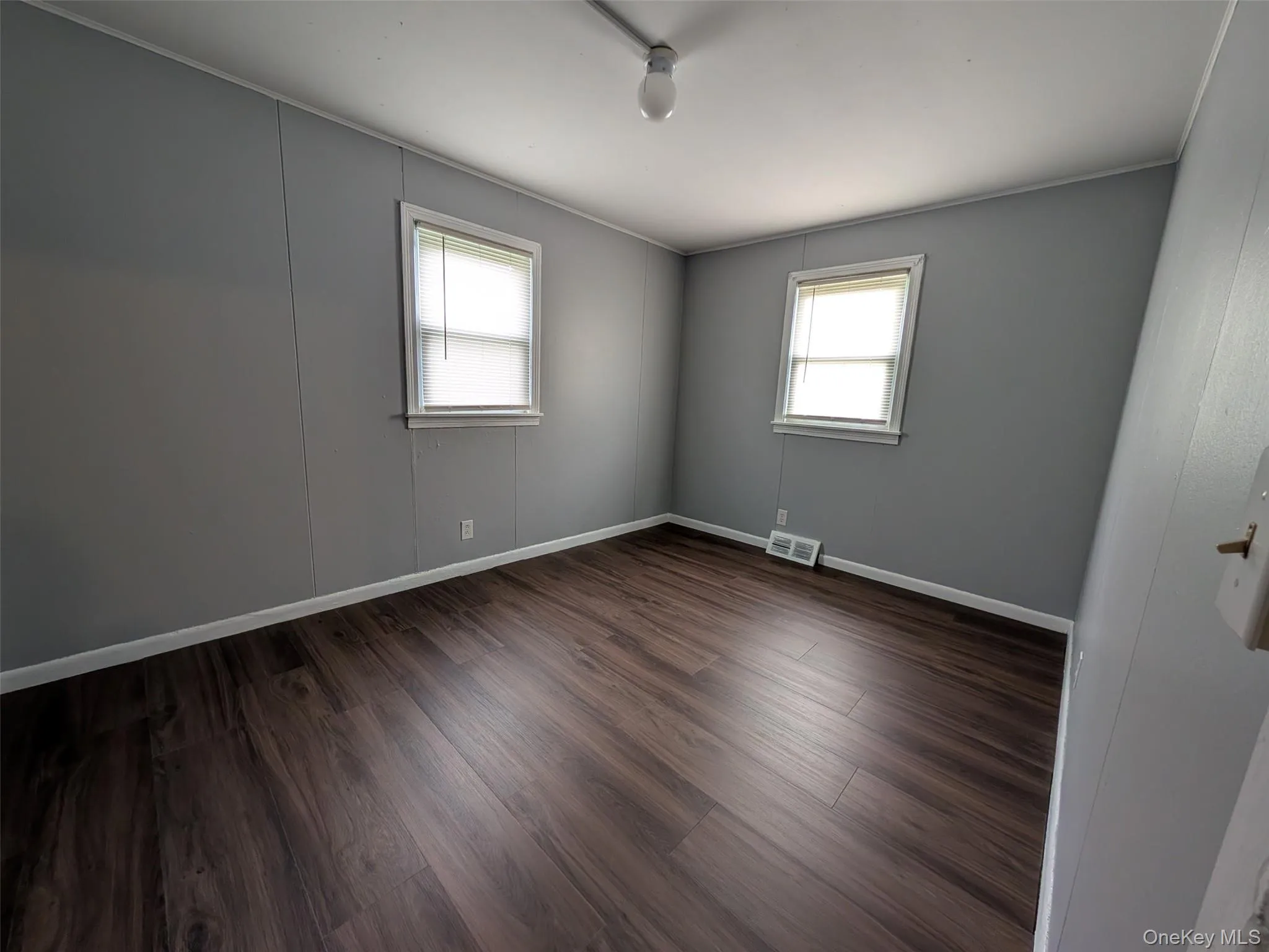 Spare room featuring dark wood-style floors and baseboards Spare room featuring dark wood-style floors and baseboards