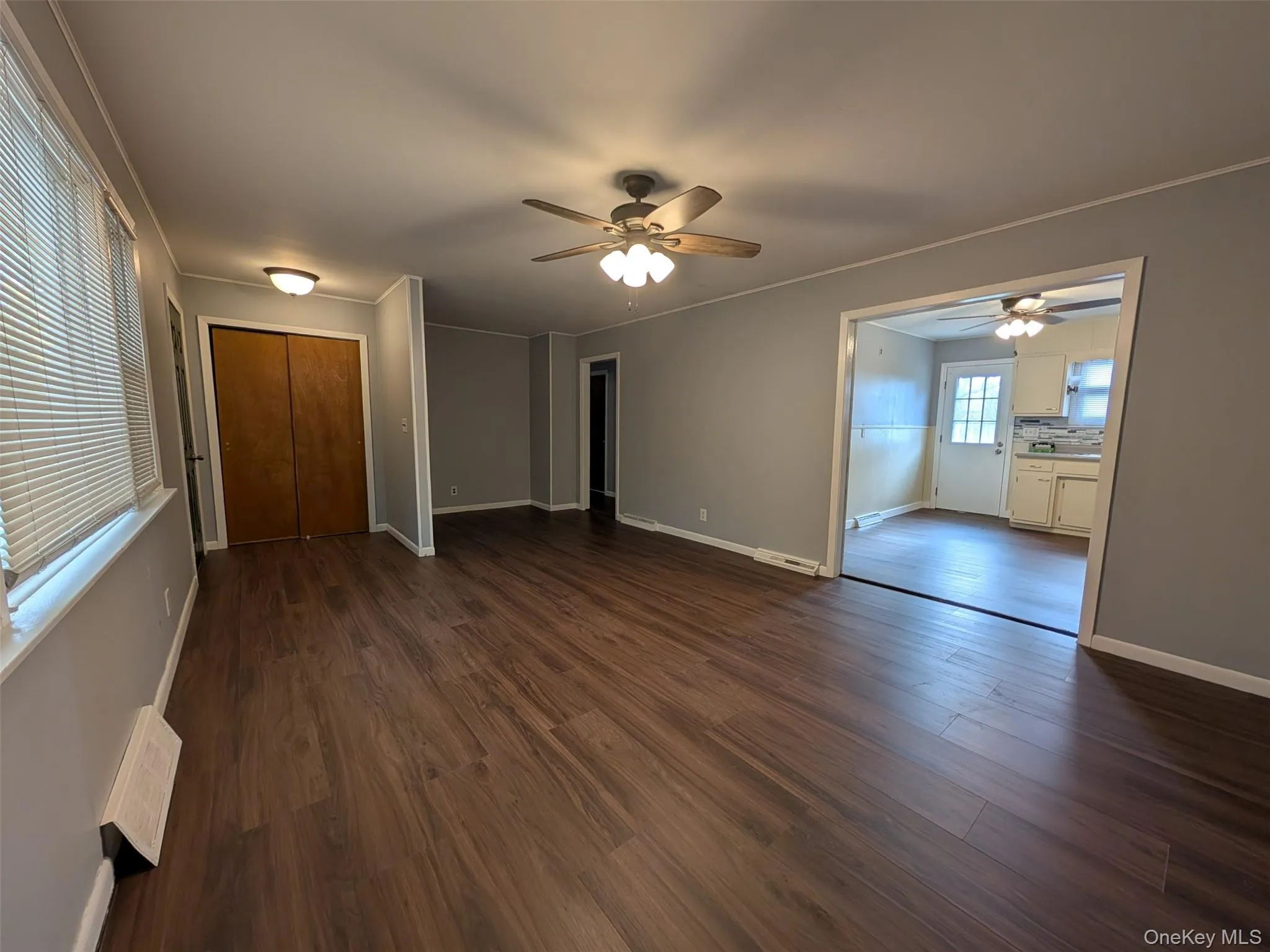 Unfurnished living room with dark wood-type flooring, crown molding, and ceiling fan Unfurnished living room with dark wood-type flooring, crown molding, and ceiling fan