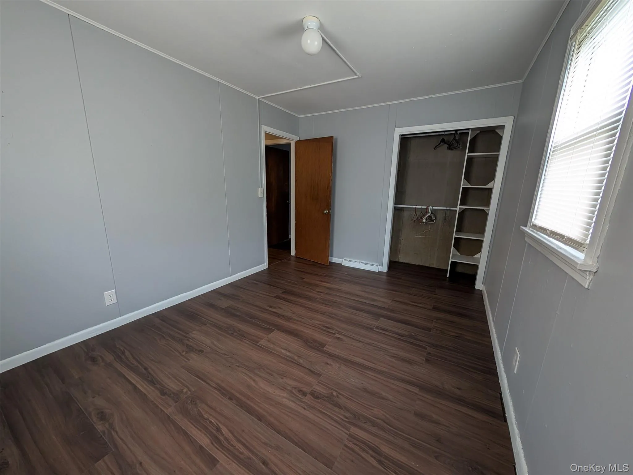 Unfurnished bedroom featuring dark wood-type flooring and a closet Unfurnished bedroom featuring dark wood-type flooring and a closet