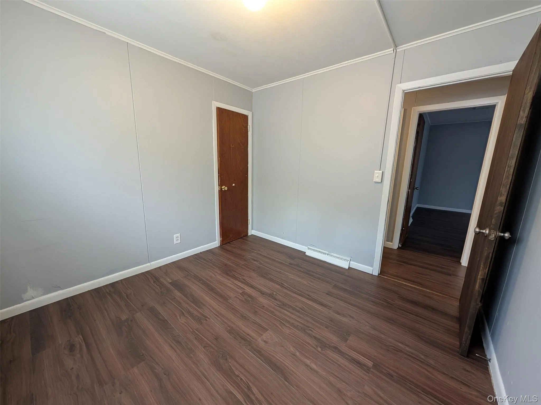 Spare room featuring dark wood finished floors and crown molding Spare room featuring dark wood finished floors and crown molding