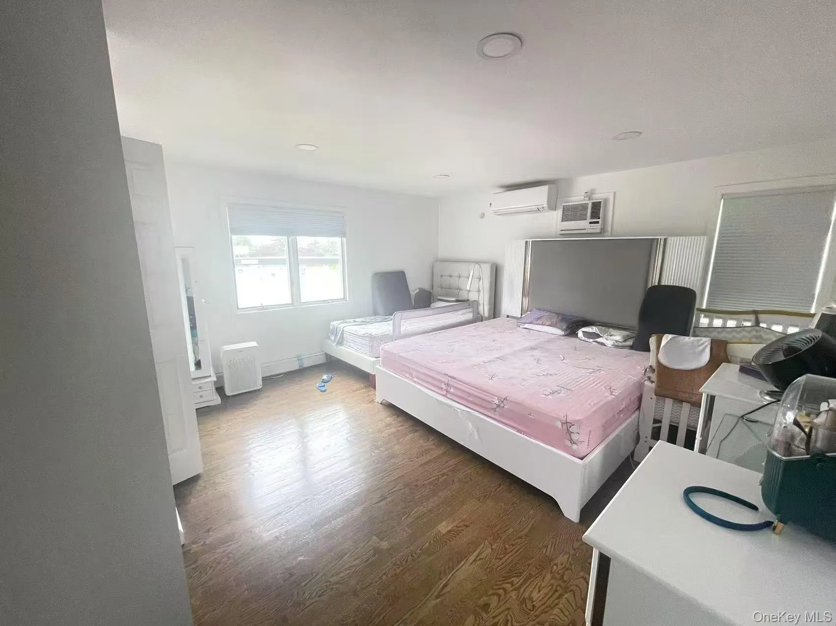 Bedroom with wood finished floors and an AC wall unit Bedroom with wood finished floors and an AC wall unit